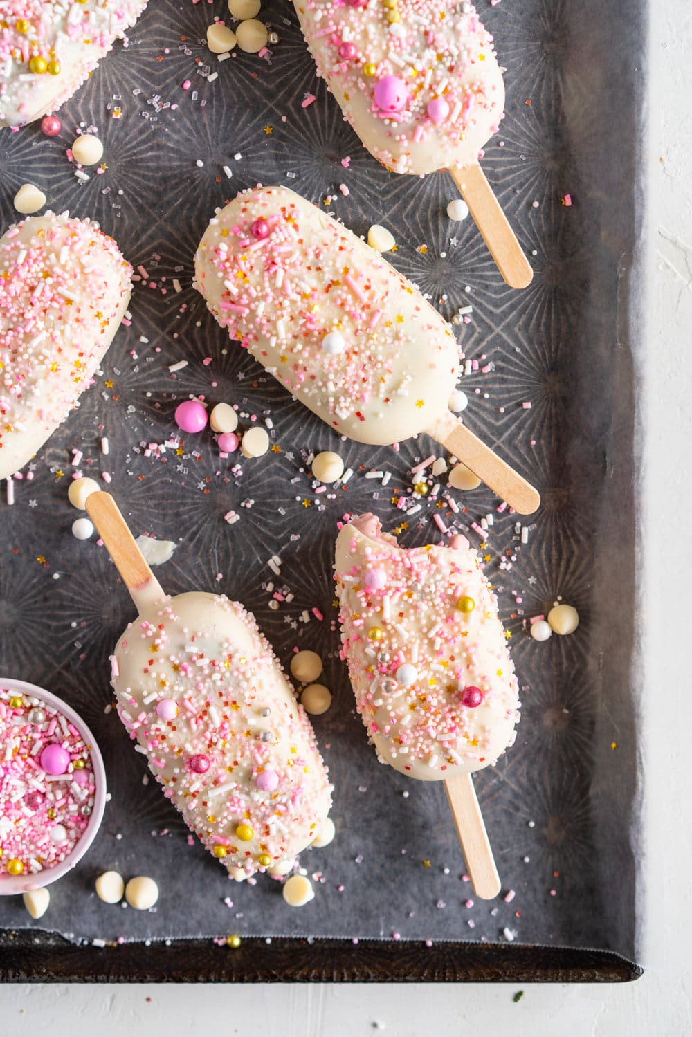A simple stir together raspberry philadelphia style ice-cream base is churned then elevated with a raspberry ripple, before being frozen into ice cream pops and finished with a super easy white chocolate magic shell and loads of sprinkles. The perfect fancy treat for summer just around the corner - these last for a long time in the freezer so are great to have on hand when the ice cream craving strikes! #icecreampop #raspberryicecream #raspberrywhitechocolate
