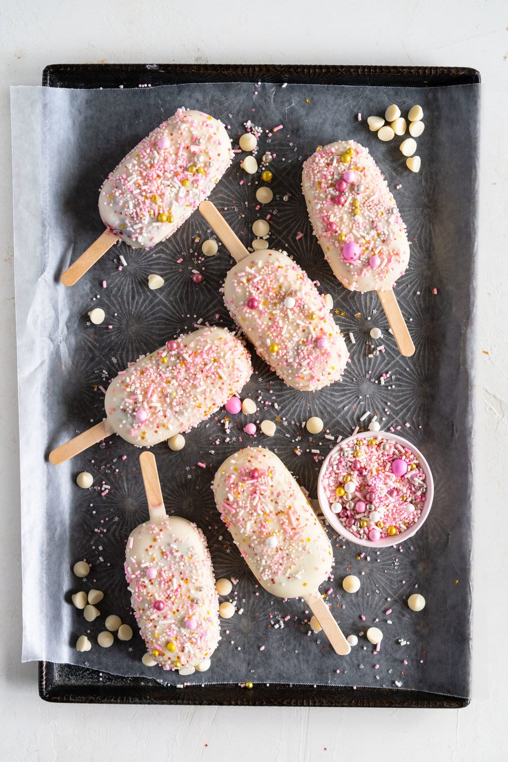 A simple stir together raspberry philadelphia style ice-cream base is churned then elevated with a raspberry ripple, before being frozen into ice cream pops and finished with a super easy white chocolate magic shell and loads of sprinkles. The perfect fancy treat for summer just around the corner - these last for a long time in the freezer so are great to have on hand when the ice cream craving strikes! #icecreampop #raspberryicecream #raspberrywhitechocolate