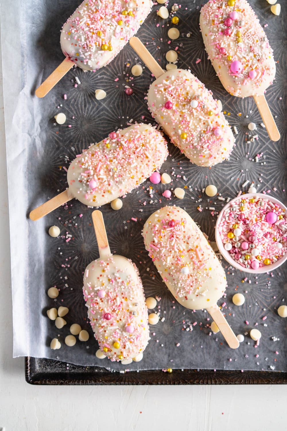A simple stir together raspberry philadelphia style ice-cream base is churned then elevated with a raspberry ripple, before being frozen into ice cream pops and finished with a super easy white chocolate magic shell and loads of sprinkles. The perfect fancy treat for summer just around the corner - these last for a long time in the freezer so are great to have on hand when the ice cream craving strikes! #icecreampop #raspberryicecream #raspberrywhitechocolate