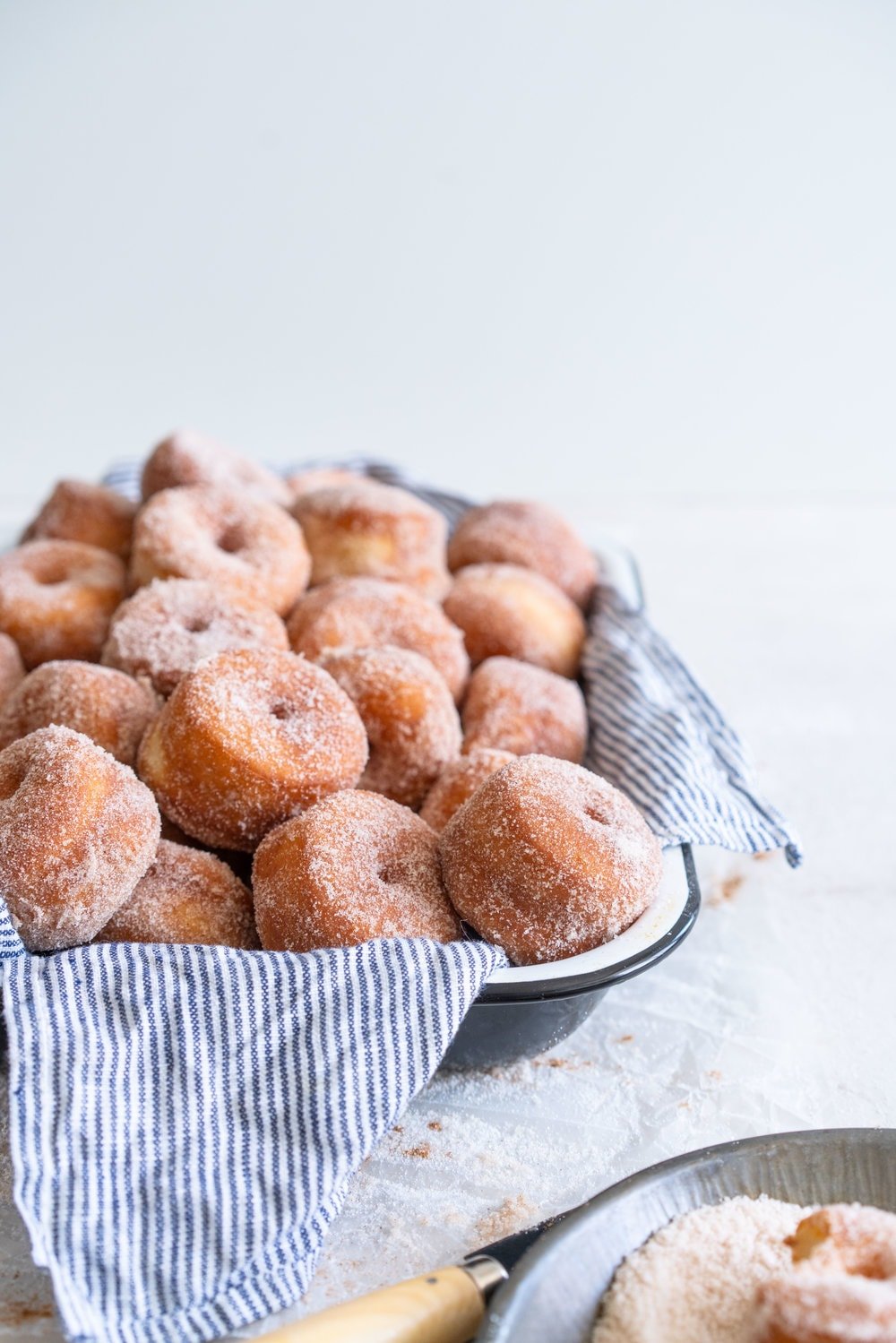 Fluffy miniature brioche doughnuts - an easy brioche dough is given an overnight rise, then rolled out and cut into tiny, perfect doughnuts, which are fried until golden brown, then rolled in cinnamon sugar. The perfect mouthful of fluffy doughnut, and sweet, spicy sugar. #briochedoughnut #cinnamonsugar #yeastdoughnut