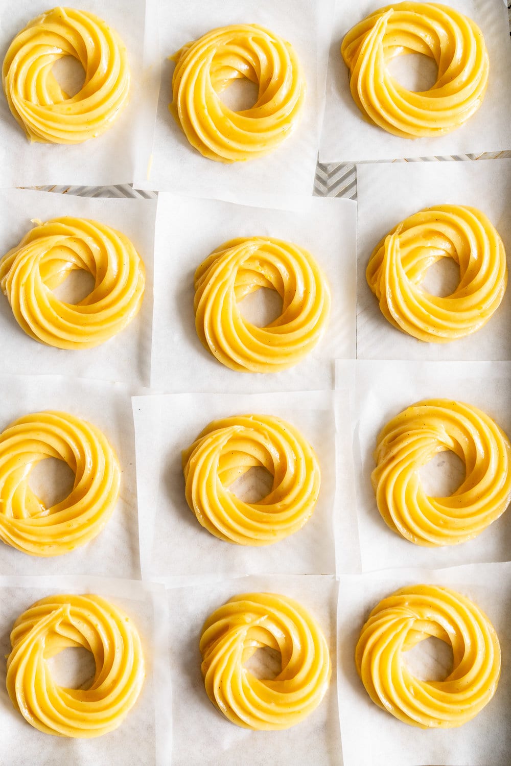 Lemon Crullers with Lemon and Honey Glaze - Fluffy, crispy lemon scented crullers are dipped in a lemon and honey glaze and finished with delicate gold leaf. Crullers are made by frying choux dough, and are a must-try if you haven't made them before! #crullers #doughnut #lemoncruller