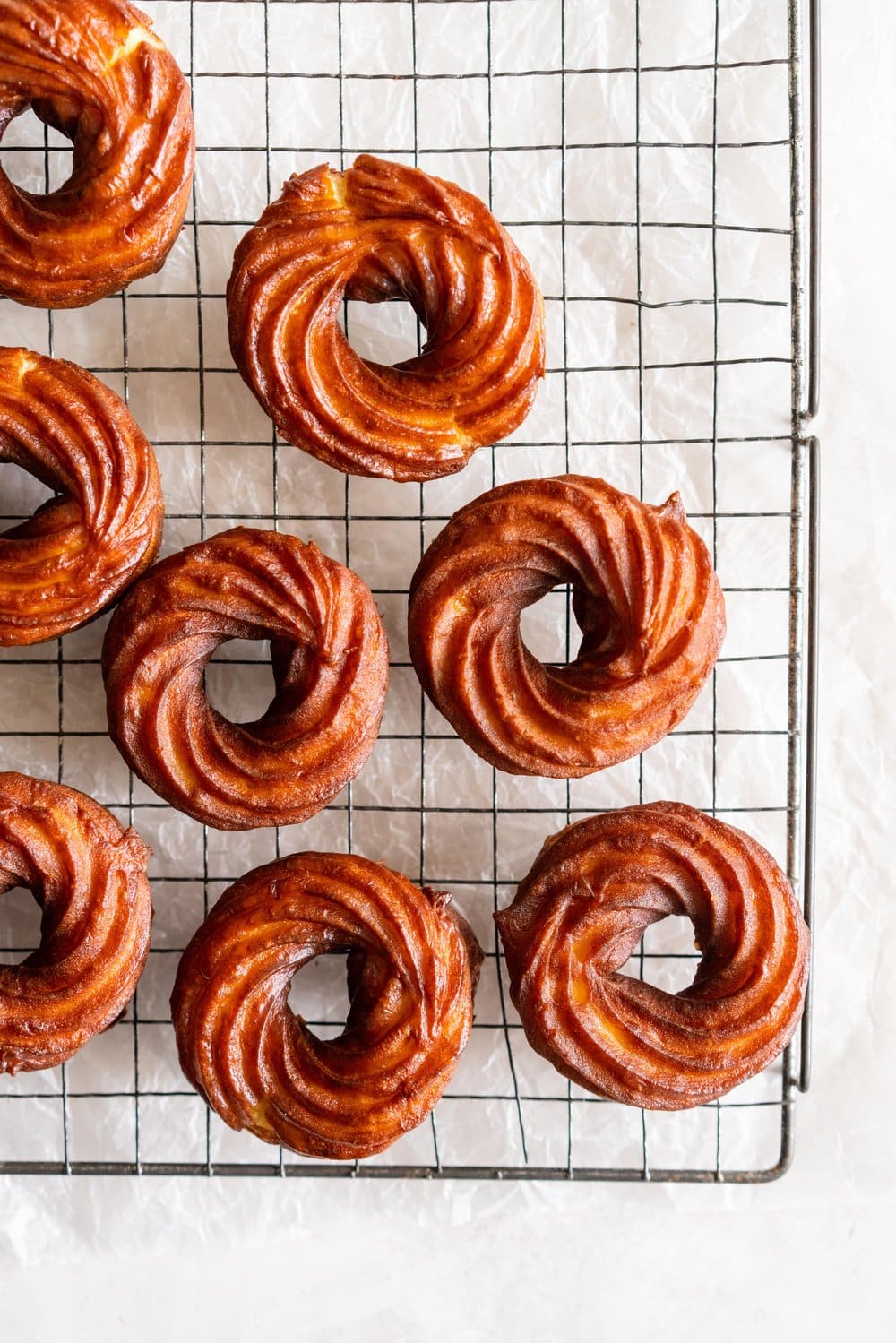 Lemon Crullers with Lemon and Honey Glaze - Fluffy, crispy lemon scented crullers are dipped in a lemon and honey glaze and finished with delicate gold leaf. Crullers are made by frying choux dough, and are a must-try if you haven't made them before! #crullers #doughnut #lemoncruller