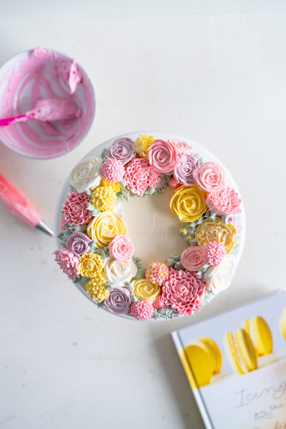 Lavender Blackberry Cake with Cream Cheese Frosting and a Piped Floral Wreath. Layers of delicately flavoured lavender cake are filled with a cream cheese frosting and blackberry jam, and topped with a beautiful floral wreath made from piped swiss meringue buttercream flowers. #pipedflowers #lavendercake #swissmeringuebuttercream #icingonthecakebook