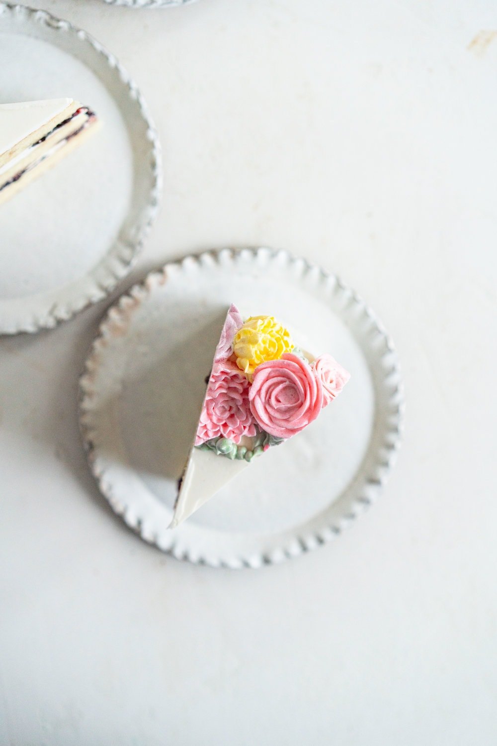 Lavender Blackberry Cake with Cream Cheese Frosting and a Piped Floral Wreath. Layers of delicately flavoured lavender cake are filled with a cream cheese frosting and blackberry jam, and topped with a beautiful floral wreath made from piped swiss meringue buttercream flowers. #pipedflowers #lavendercake #swissmeringuebuttercream #icingonthecakebook