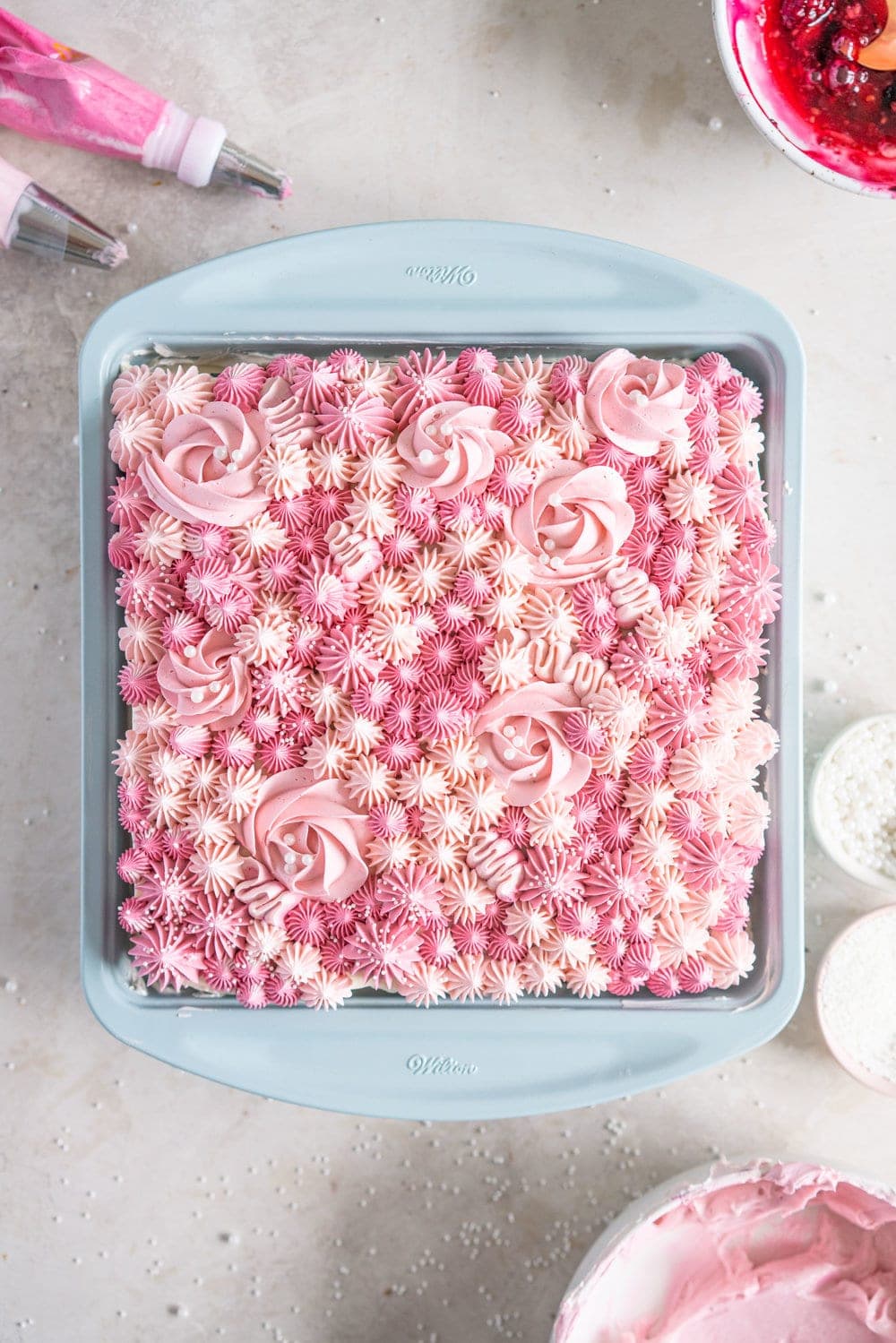 A super easy but delicious rich one bowl chocolate sheet cake is filled with a simple mixed berry cake filling and finished with a piped top using vanilla bean swiss meringue buttercream. This cake is baked in the new Wilton Texturra performance non-stick bakeware, and is finished with simple but beautiful piping in different shades of pink using various piping tips. This cake is simple yet elegant and is a perfect easy alternative to a layer cake. #chocolatecake #wilton #onebowlchocolatecake