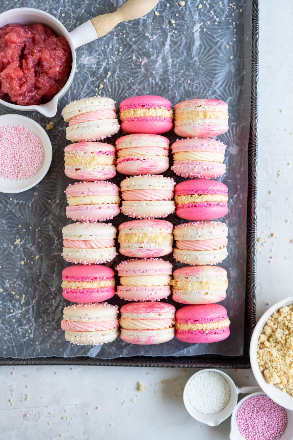 Strawberry shortcake macarons - French Macaron shells are filled with a strawberry filling, cream cheese german buttercream, and finished with a brown butter pie crumb crunch. These encompass summer in every bite. #strawberryshortcake #piecrumb #strawberrymacaron