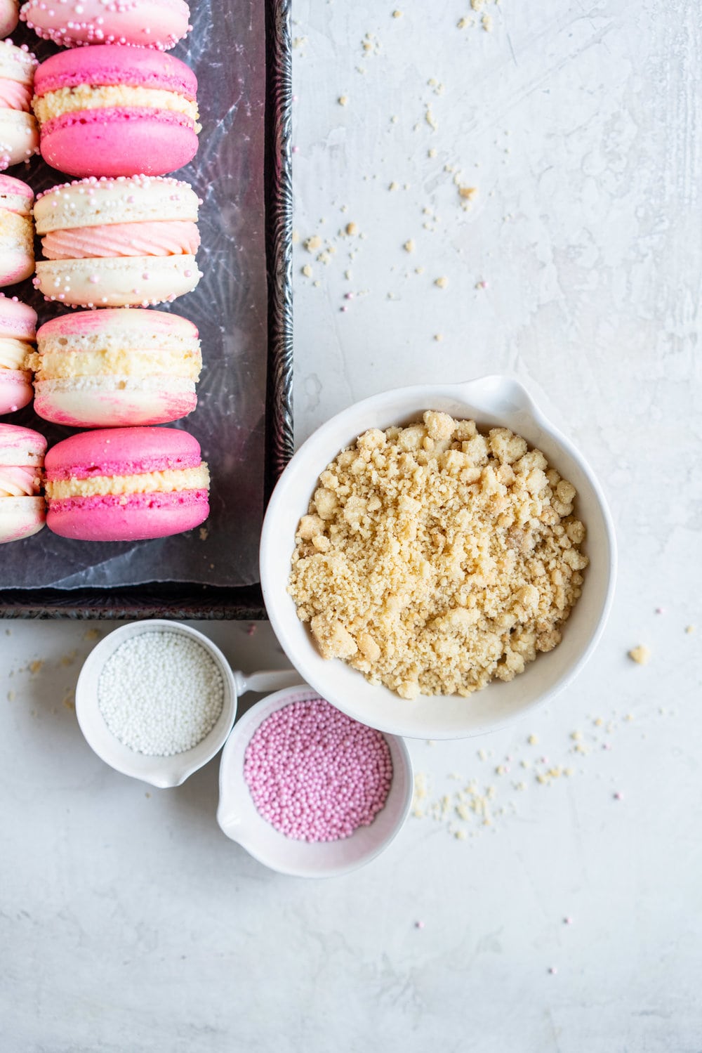 Strawberry shortcake macarons - French Macaron shells are filled with a strawberry filling, cream cheese german buttercream, and finished with a brown butter pie crumb crunch. These encompass summer in every bite. #strawberryshortcake #piecrumb #strawberrymacaron
