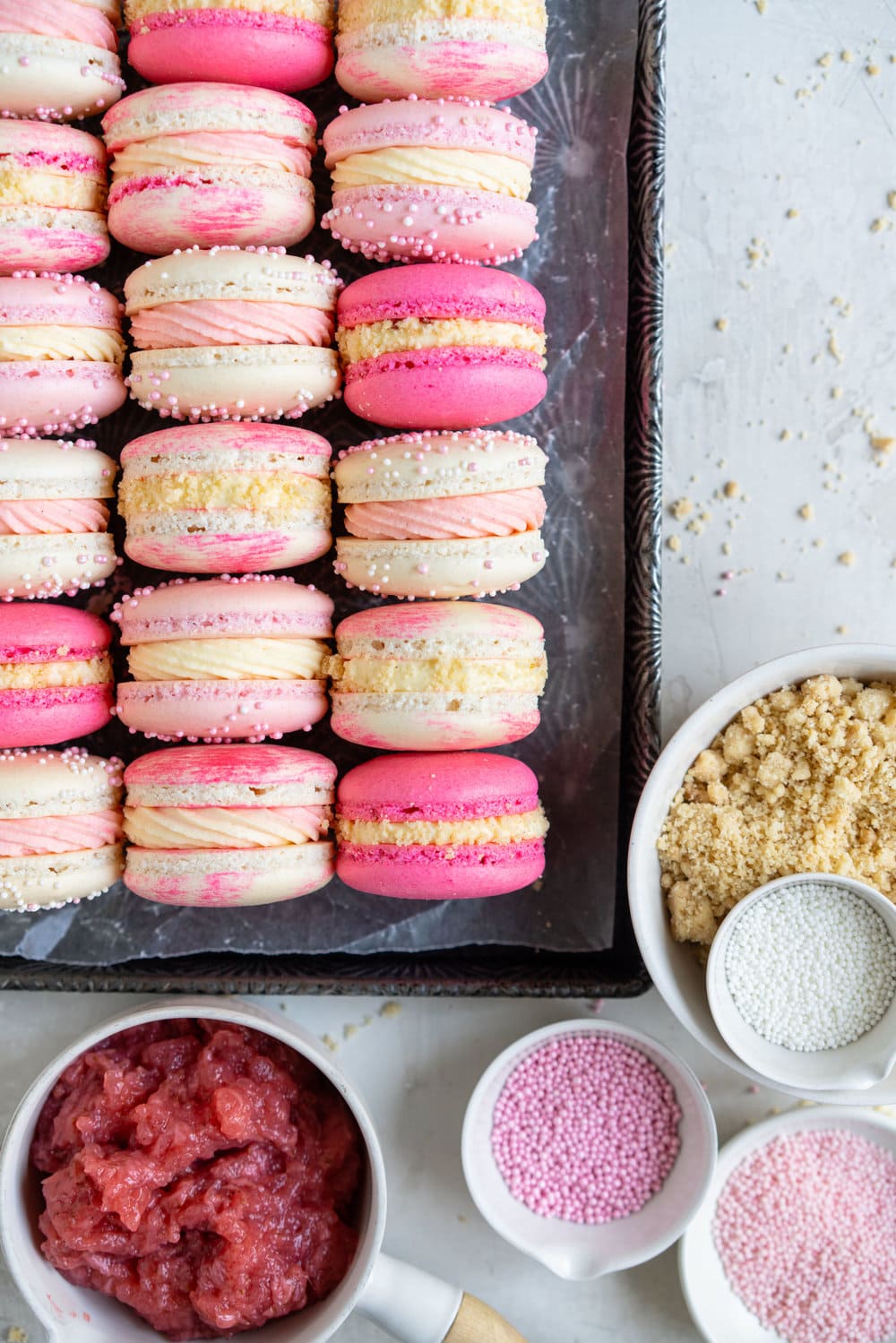 Strawberry shortcake macarons - French Macaron shells are filled with a strawberry filling, cream cheese german buttercream, and finished with a brown butter pie crumb crunch. These encompass summer in every bite. #strawberryshortcake #piecrumb #strawberrymacaron