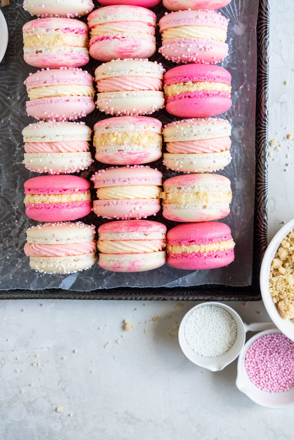 Strawberry shortcake macarons - French Macaron shells are filled with a strawberry filling, cream cheese german buttercream, and finished with a brown butter pie crumb crunch. These encompass summer in every bite. #strawberryshortcake #piecrumb #strawberrymacaron