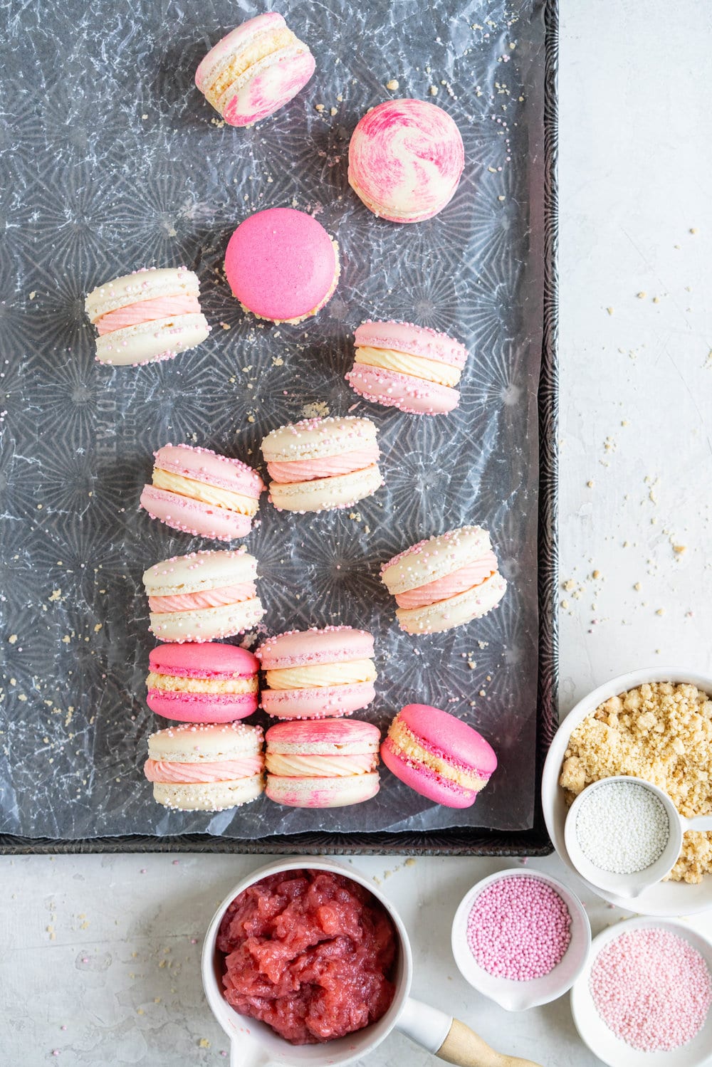 Strawberry shortcake macarons - French Macaron shells are filled with a strawberry filling, cream cheese german buttercream, and finished with a brown butter pie crumb crunch. These encompass summer in every bite. #strawberryshortcake #piecrumb #strawberrymacaron