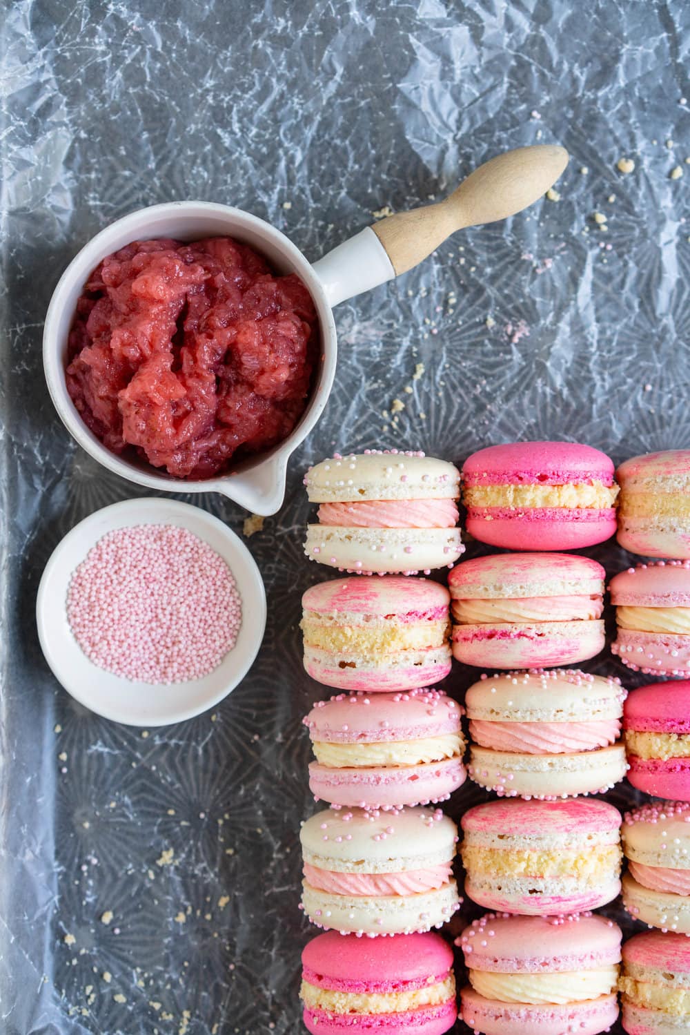 Strawberry shortcake macarons - French Macaron shells are filled with a strawberry filling, cream cheese german buttercream, and finished with a brown butter pie crumb crunch. These encompass summer in every bite. #strawberryshortcake #piecrumb #strawberrymacaron