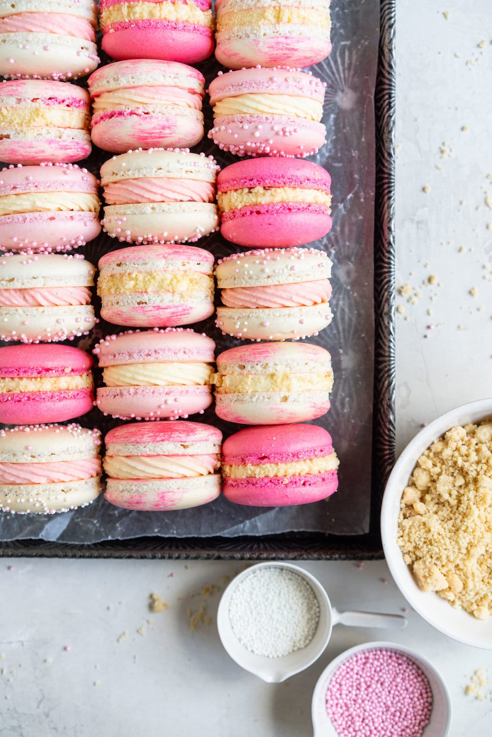 Strawberry shortcake macarons - French Macaron shells are filled with a strawberry filling, cream cheese german buttercream, and finished with a brown butter pie crumb crunch. These encompass summer in every bite. #strawberryshortcake #piecrumb #strawberrymacaron