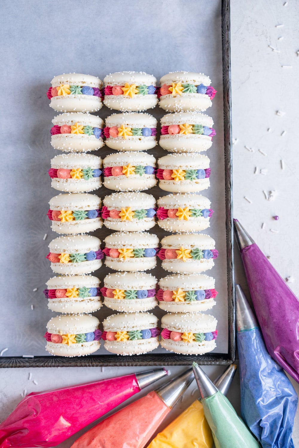 Rainbow macarons for pride - vanilla bean French macaron shells are filled with a vanilla bean swiss meringue buttercream, which is tinted the colours of the rainbow and piped around the shell. These are the perfect rainbow macaron for any occasion! #pride #Frenchmacarons #glutenfree #rainbowmacarons