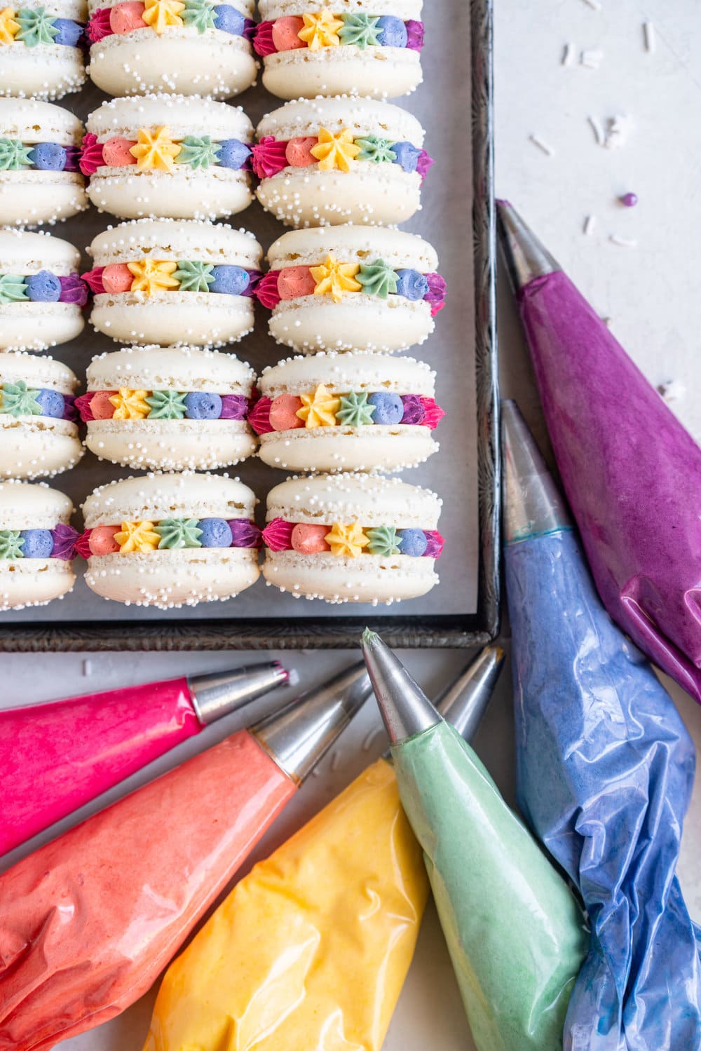 Rainbow macarons for pride - vanilla bean French macaron shells are filled with a vanilla bean swiss meringue buttercream, which is tinted the colours of the rainbow and piped around the shell. These are the perfect rainbow macaron for any occasion! #pride #Frenchmacarons #glutenfree #rainbowmacarons