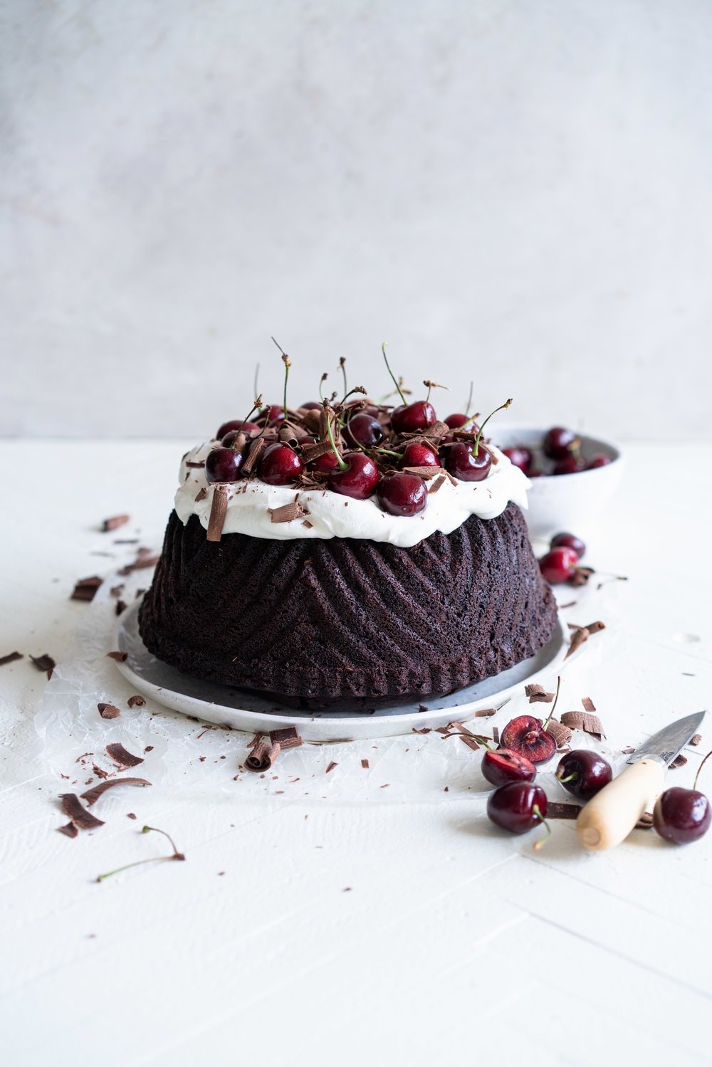 Black forest bundt cake - a rich, tender, chocolate cherry bundt cake that is studded with cherries is topped with fresh softly whipped cream, fresh cherries, and chocolate curls #blackforest #chocolatecherrybundt #chocolatebundtcake