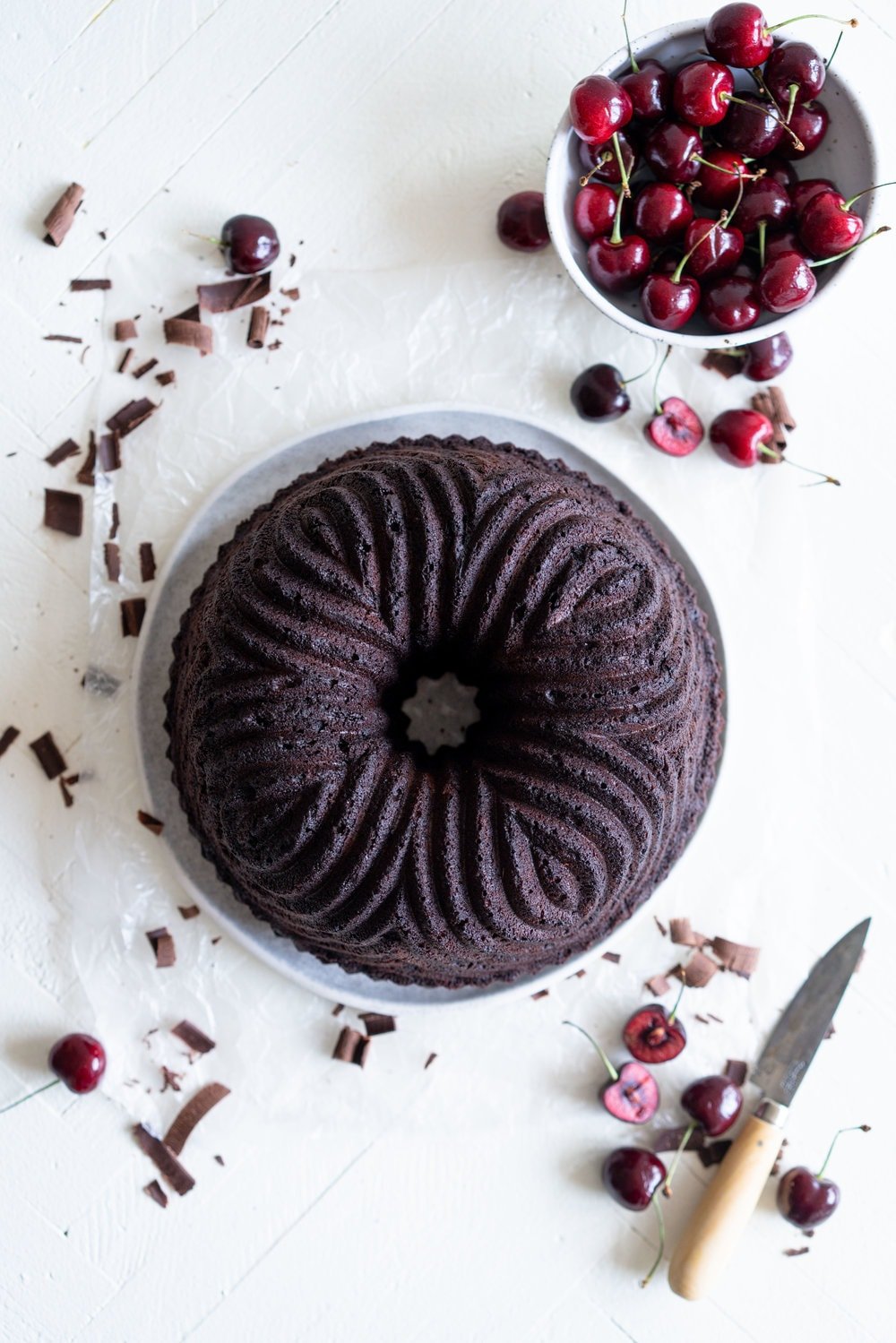 Black forest bundt cake - a rich, tender, chocolate cherry bundt cake that is studded with cherries is topped with fresh softly whipped cream, fresh cherries, and chocolate curls #blackforest #chocolatecherrybundt #chocolatebundtcake