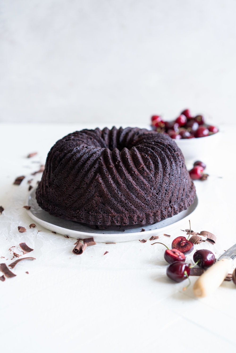 Black forest bundt cake - a rich, tender, chocolate cherry bundt cake that is studded with cherries is topped with fresh softly whipped cream, fresh cherries, and chocolate curls #blackforest #chocolatecherrybundt #chocolatebundtcake
