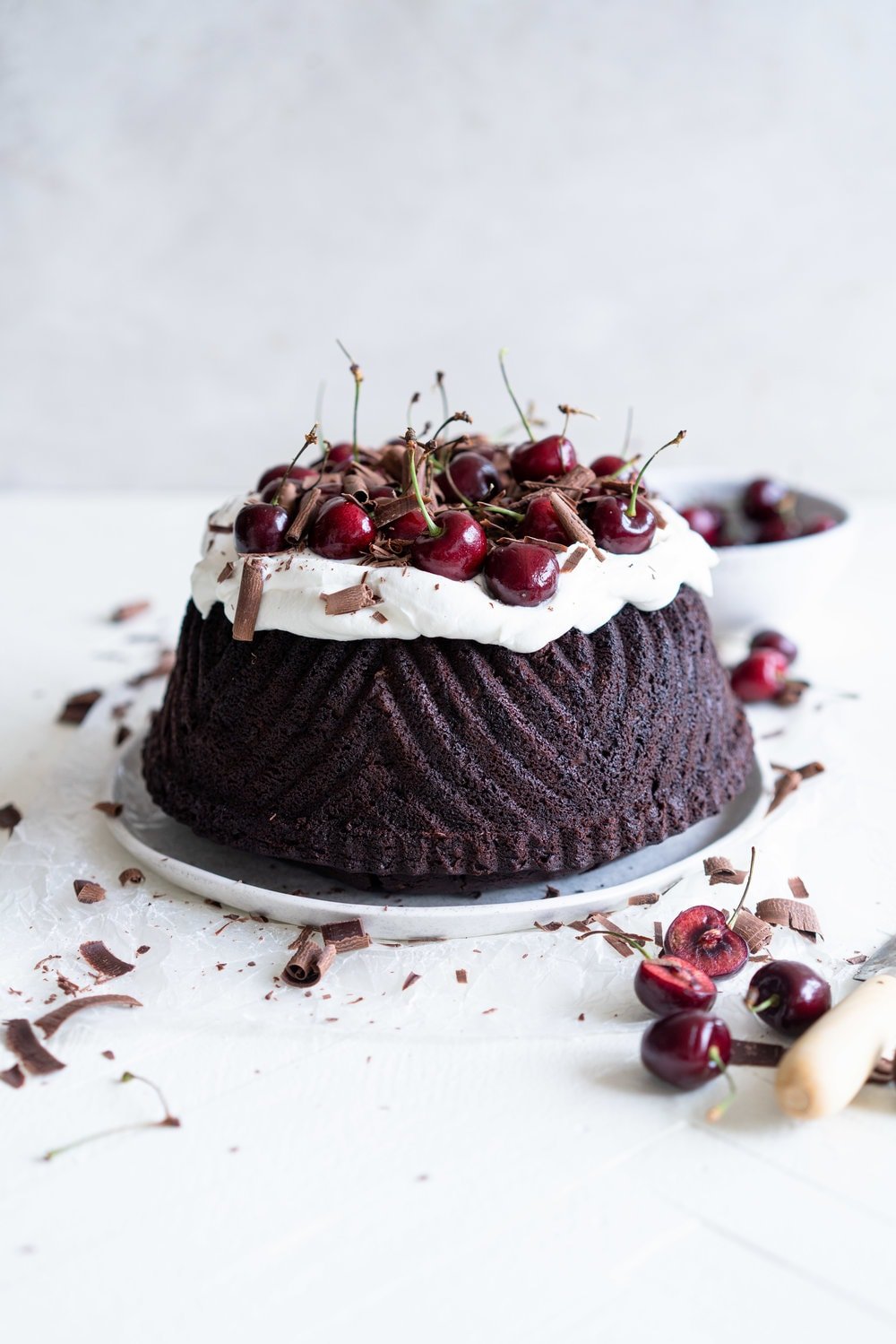 Black forest bundt cake - a rich, tender, chocolate cherry bundt cake that is studded with cherries is topped with fresh softly whipped cream, fresh cherries, and chocolate curls #blackforest #chocolatecherrybundt #chocolatebundtcake