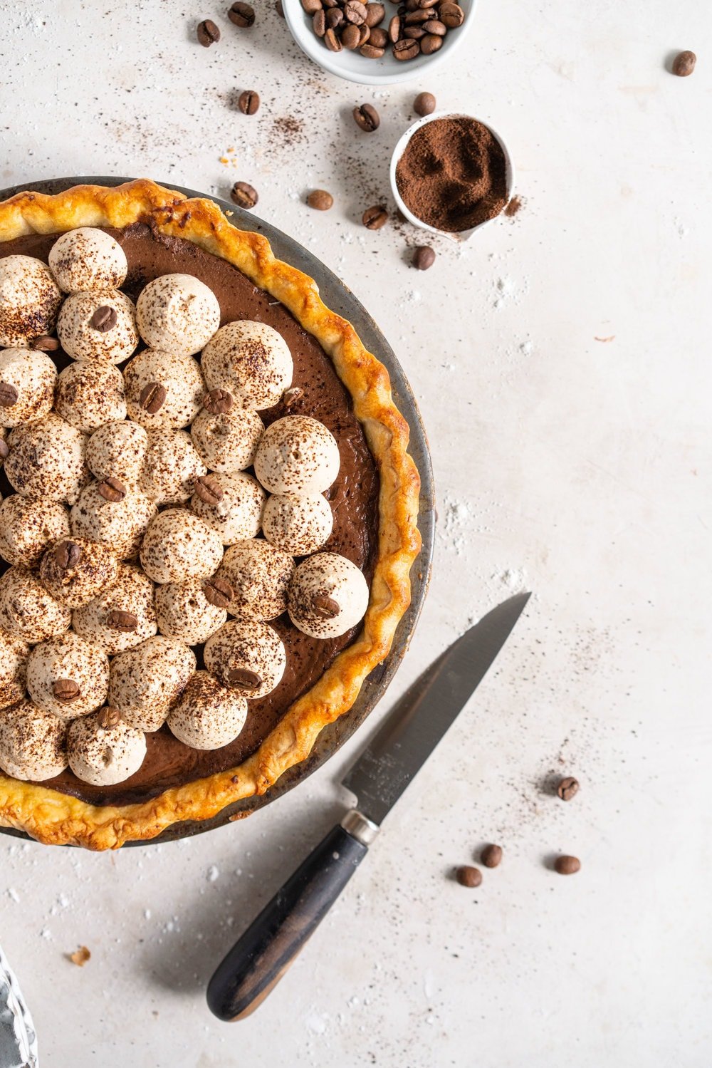 Mocha Cream pie with espresso whipped cream - a crispy blind baked pie crust is filled with a mocha pudding filling and topped with clouds of espresso flavoured whipped cream, before being finished off with coffee beans and espresso powder. This pie is super simple to make and is a coffee lover's dream. #mochapie #creampie #mocha #cloudykitchenpie