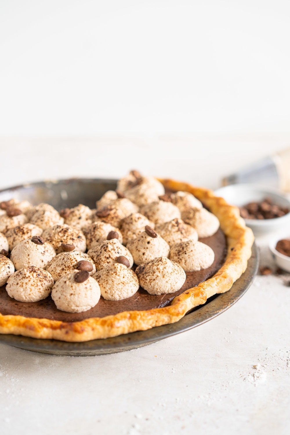 Mocha Cream pie with espresso whipped cream - a crispy blind baked pie crust is filled with a mocha pudding filling and topped with clouds of espresso flavoured whipped cream, before being finished off with coffee beans and espresso powder. This pie is super simple to make and is a coffee lover's dream. #mochapie #creampie #mocha #cloudykitchenpie