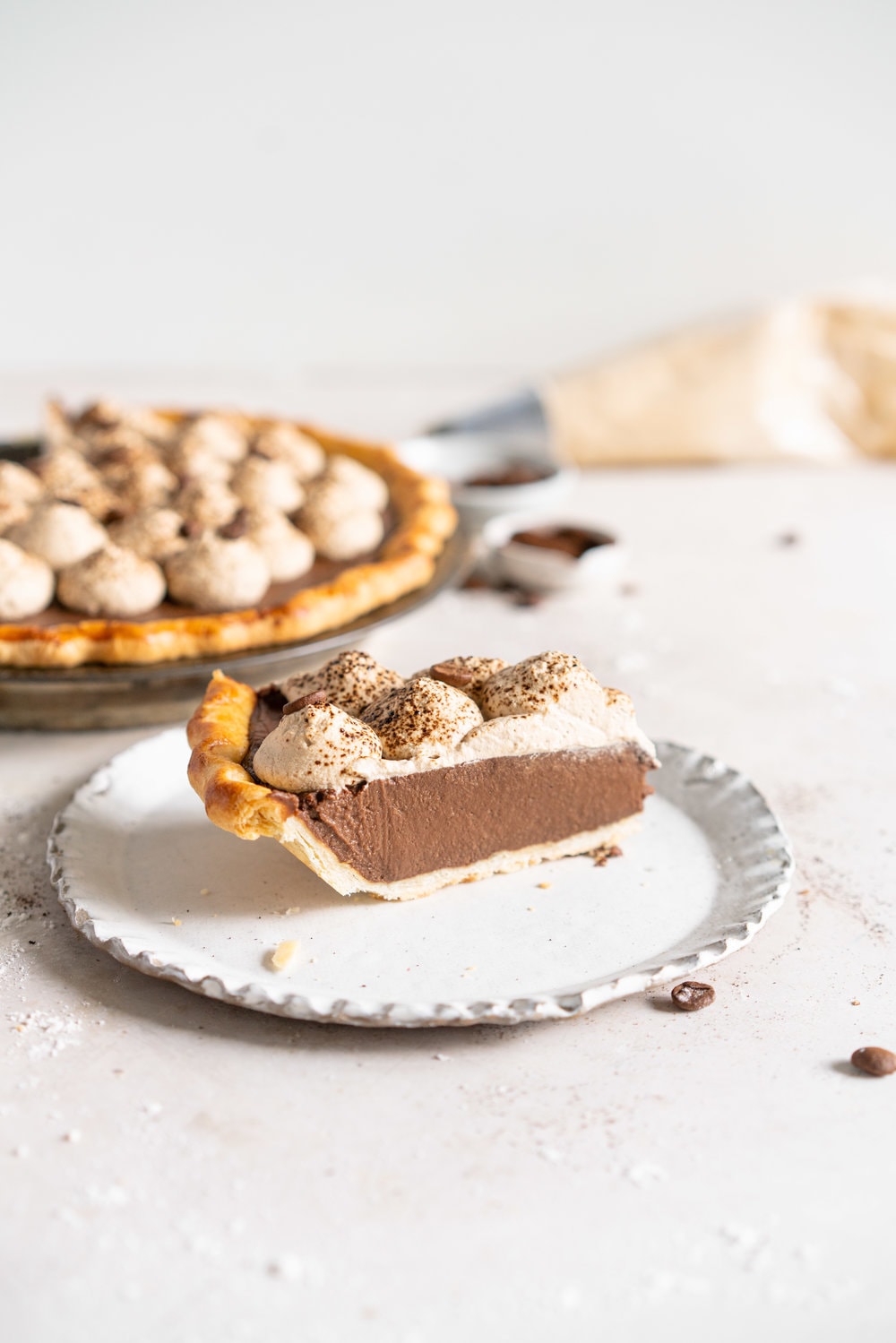 Mocha Cream pie with espresso whipped cream - a crispy blind baked pie crust is filled with a mocha pudding filling and topped with clouds of espresso flavoured whipped cream, before being finished off with coffee beans and espresso powder. This pie is super simple to make and is a coffee lover's dream. #mochapie #creampie #mocha #cloudykitchenpie