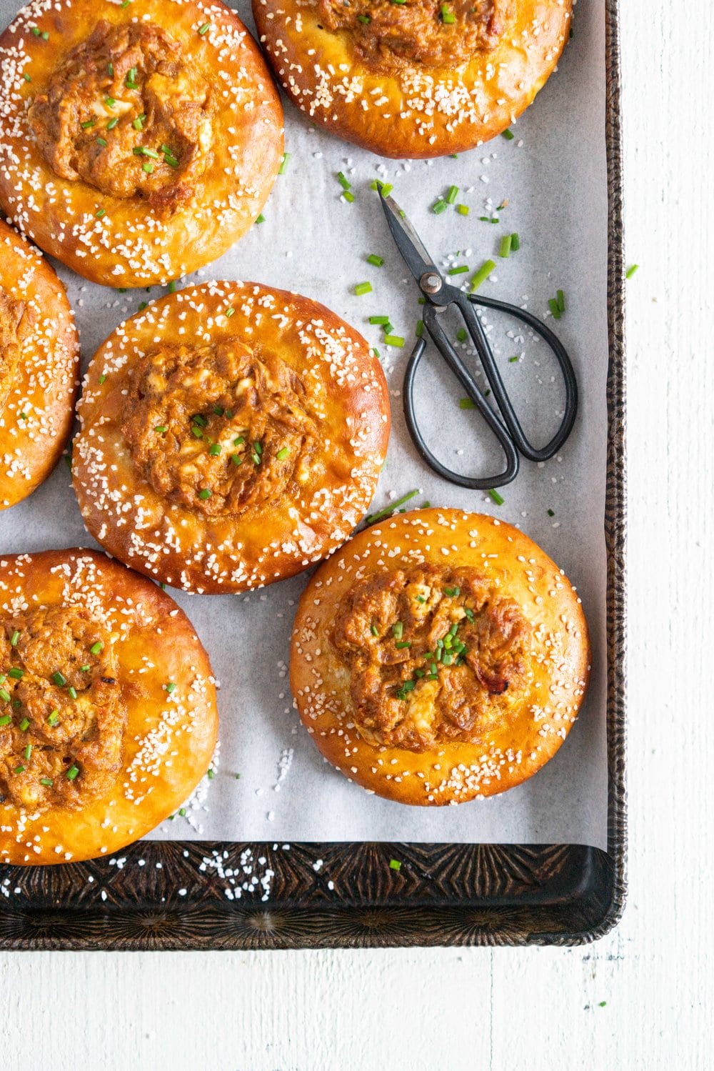 Caramelised Onion, Goat Cheese, and Sundried Tomato Pesto Pretzel Buns - chewy, golden brown pretzel buns are filled with a flavourful filling before being baked to golden brown perfection. These would make the most perfect snack or light meal, and are great for feeding a crowd! #pretzelbun #pesto #sundriedtomatopesto