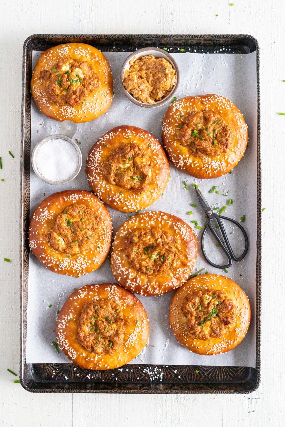Caramelised Onion, Goat Cheese, and Sundried Tomato Pesto Pretzel Buns - chewy, golden brown pretzel buns are filled with a flavourful filling before being baked to golden brown perfection. These would make the most perfect snack or light meal, and are great for feeding a crowd! #pretzelbun #pesto #sundriedtomatopesto