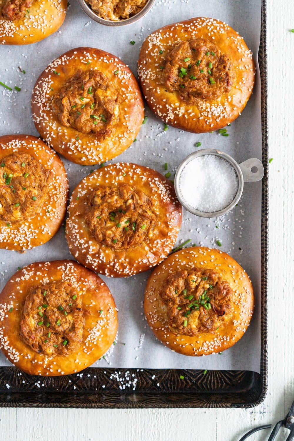 Caramelised Onion, Goat Cheese, and Sundried Tomato Pesto Pretzel Buns - chewy, golden brown pretzel buns are filled with a flavourful filling before being baked to golden brown perfection. These would make the most perfect snack or light meal, and are great for feeding a crowd! #pretzelbun #pesto #sundriedtomatopesto