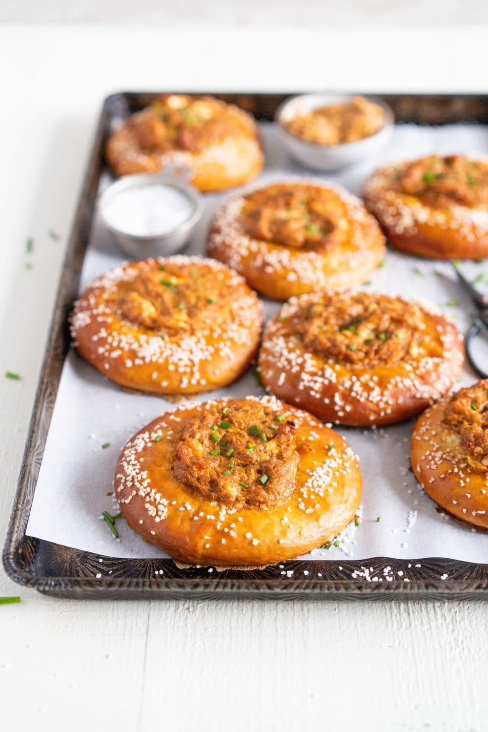 Caramelised Onion, Goat Cheese, and Sundried Tomato Pesto Pretzel Buns - chewy, golden brown pretzel buns are filled with a flavourful filling before being baked to golden brown perfection. These would make the most perfect snack or light meal, and are great for feeding a crowd! #pretzelbun #pesto #sundriedtomatopesto