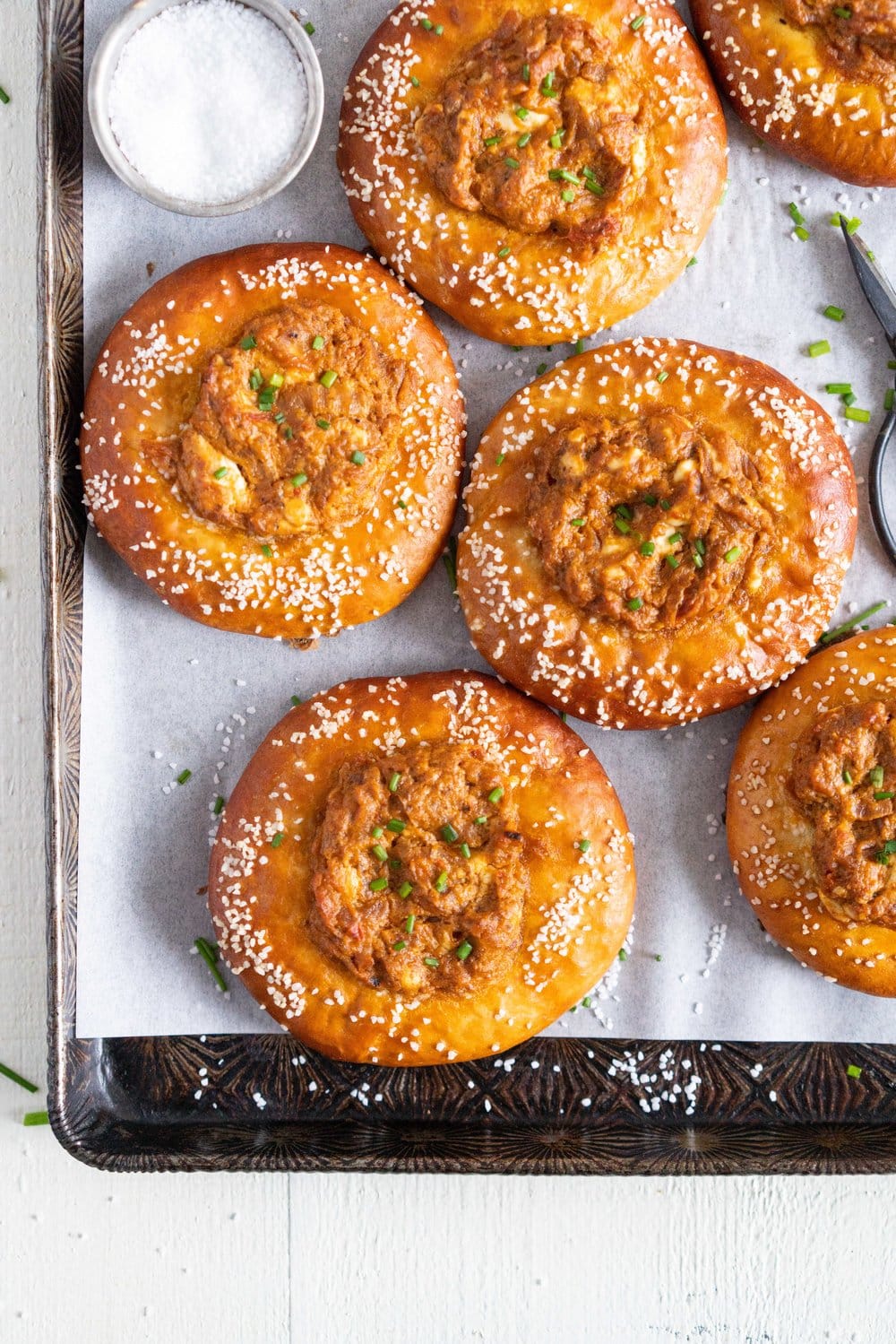 Caramelised Onion, Goat Cheese, and Sundried Tomato Pesto Pretzel Buns - chewy, golden brown pretzel buns are filled with a flavourful filling before being baked to golden brown perfection. These would make the most perfect snack or light meal, and are great for feeding a crowd! #pretzelbun #pesto #sundriedtomatopesto