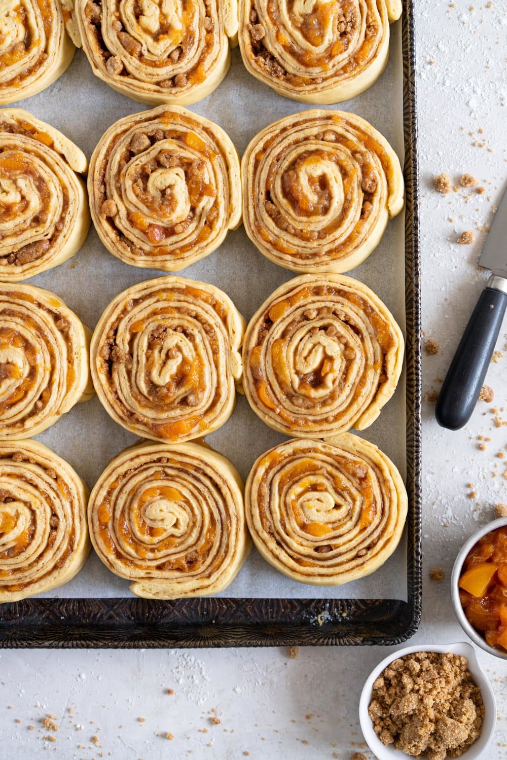 Laminated brioche cinnamon buns with peach compote and brown butter streusel. Soft and fluffy brioche is layered with cinnamon sugar, then filled with a brown butter streusel and peach compote, and finished with a powdered sugar glaze. These are the perfect summer treat. #briochebuns #cinnamonbuns #laminatedbriochebuns #peachcompote