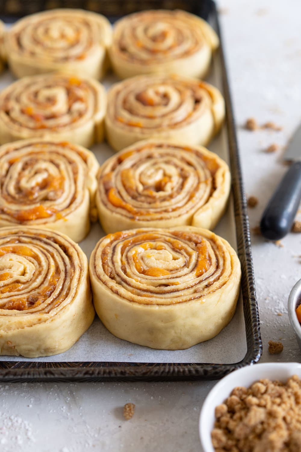Laminated brioche cinnamon buns with peach compote and brown butter streusel. Soft and fluffy brioche is layered with cinnamon sugar, then filled with a brown butter streusel and peach compote, and finished with a powdered sugar glaze. These are the perfect summer treat. #briochebuns #cinnamonbuns #laminatedbriochebuns #peachcompote