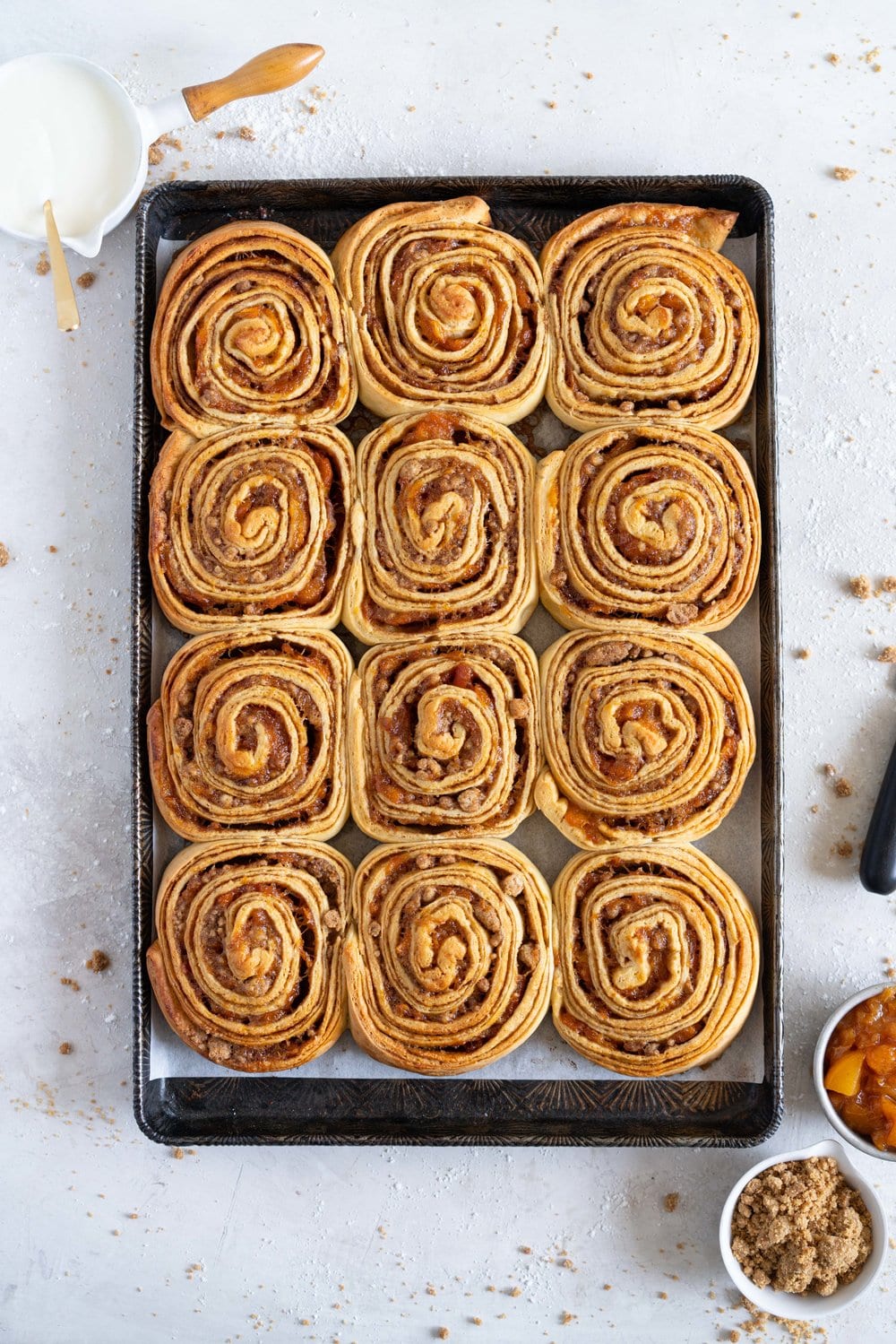 Laminated brioche cinnamon buns with peach compote and brown butter streusel. Soft and fluffy brioche is layered with cinnamon sugar, then filled with a brown butter streusel and peach compote, and finished with a powdered sugar glaze. These are the perfect summer treat. #briochebuns #cinnamonbuns #laminatedbriochebuns #peachcompote