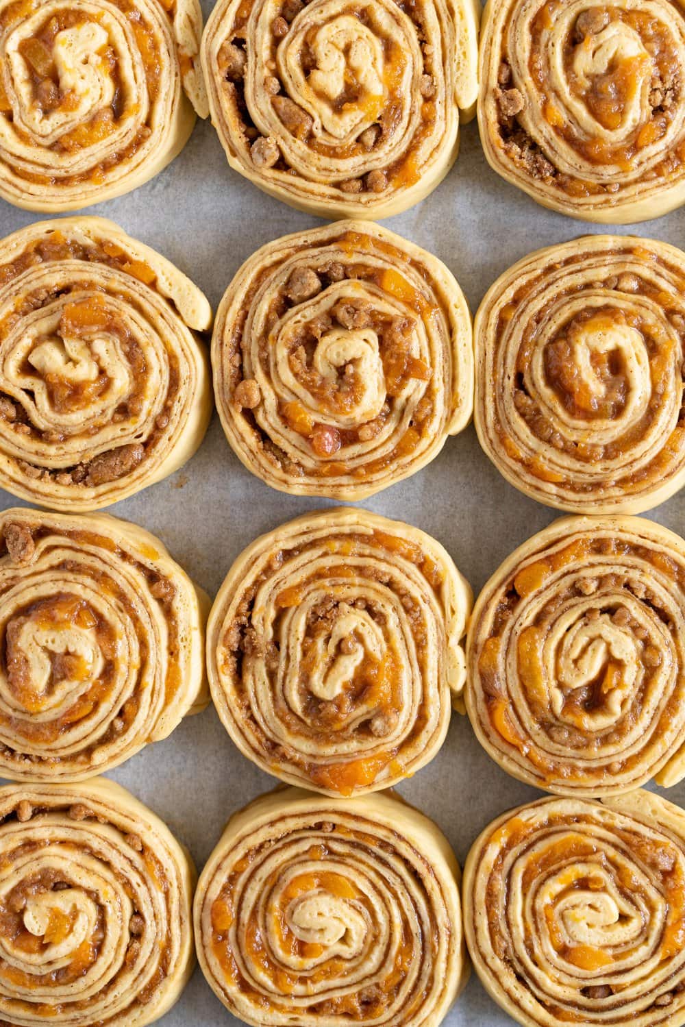 Laminated brioche cinnamon buns with peach compote and brown butter streusel. Soft and fluffy brioche is layered with cinnamon sugar, then filled with a brown butter streusel and peach compote, and finished with a powdered sugar glaze. These are the perfect summer treat. #briochebuns #cinnamonbuns #laminatedbriochebuns #peachcompote
