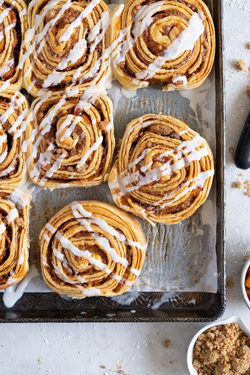 Laminated brioche cinnamon buns with peach compote and brown butter streusel. Soft and fluffy brioche is layered with cinnamon sugar, then filled with a brown butter streusel and peach compote, and finished with a powdered sugar glaze. These are the perfect summer treat. #briochebuns #cinnamonbuns #laminatedbriochebuns #peachcompote