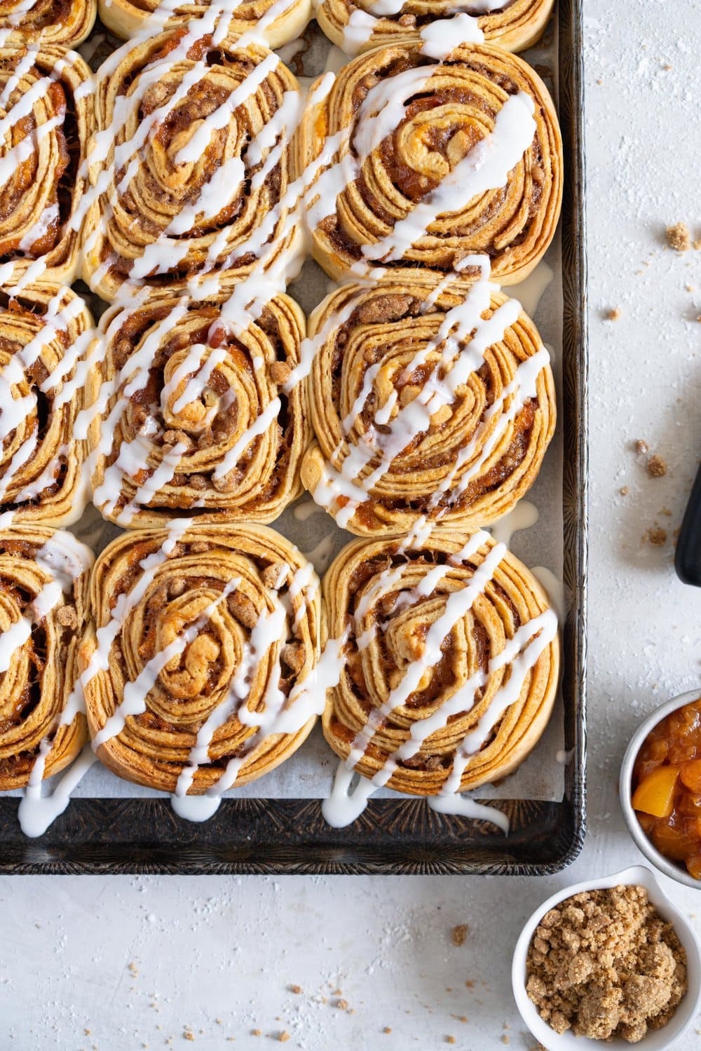 Laminated brioche cinnamon buns with peach compote and brown butter streusel. Soft and fluffy brioche is layered with cinnamon sugar, then filled with a brown butter streusel and peach compote, and finished with a powdered sugar glaze. These are the perfect summer treat. #briochebuns #cinnamonbuns #laminatedbriochebuns #peachcompote