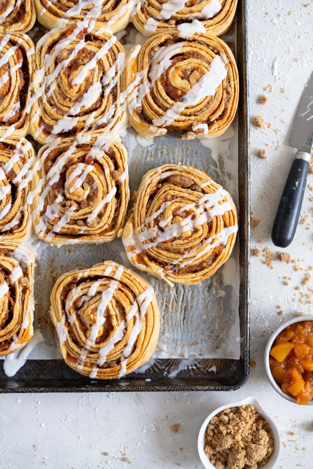 Laminated brioche cinnamon buns with peach compote and brown butter streusel. Soft and fluffy brioche is layered with cinnamon sugar, then filled with a brown butter streusel and peach compote, and finished with a powdered sugar glaze. These are the perfect summer treat. #briochebuns #cinnamonbuns #laminatedbriochebuns #peachcompote