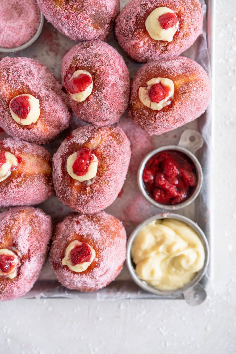 Brioche Doughnuts with Vanilla Bean Pastry Cream and Roasted Strawberry Filling. Roasting strawberries brings out the most amazing sweet flavour, which pairs so perfectly with the smooth vanilla bean pastry cream and fluffy brioche doughnut dough which is rolled in a freeze dried strawberry sugar. #briochedoughnut #strawberrydoughnut #roastedstrawberry