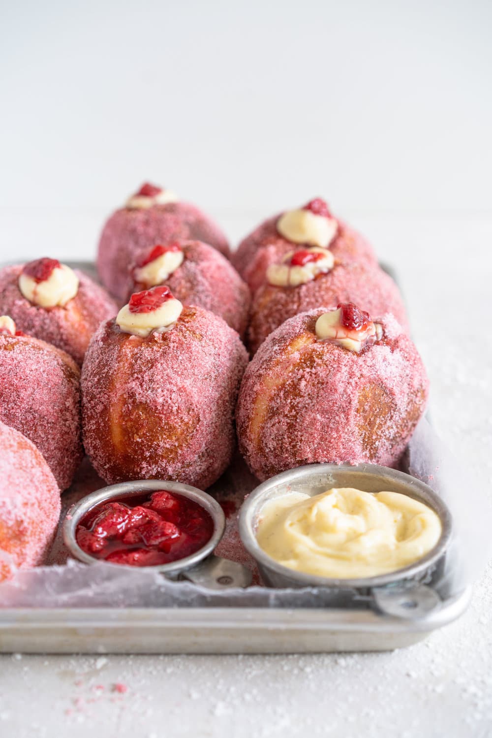 Brioche Doughnuts with Vanilla Bean Pastry Cream and Roasted Strawberry Filling. Roasting strawberries brings out the most amazing sweet flavour, which pairs so perfectly with the smooth vanilla bean pastry cream and fluffy brioche doughnut dough which is rolled in a freeze dried strawberry sugar. #briochedoughnut #strawberrydoughnut #roastedstrawberry