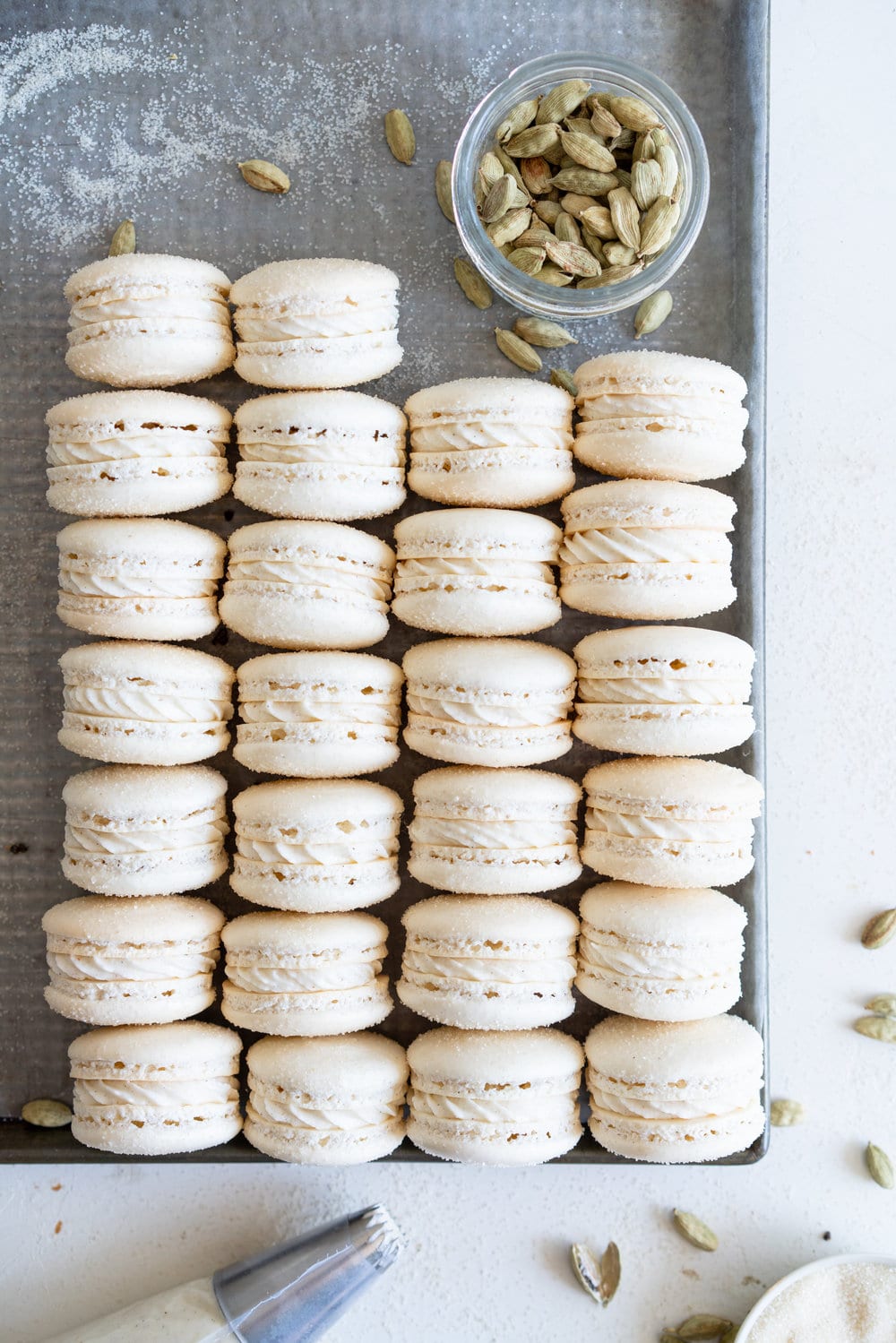 Golden Sugar Macarons with Cardamom Cream Cheese Filling. These French macarons are made with golden sugar, sprinkled with the sugar to give them a sparkly top, and filled with a smooth cardamom cream cheese filling. These are an easy gluten free treat, and this is a great go-to macaron recipe, filled with tips and tricks to help you master french macarons! #frenchmacarons #goldensugar #cardamomcreamcheese