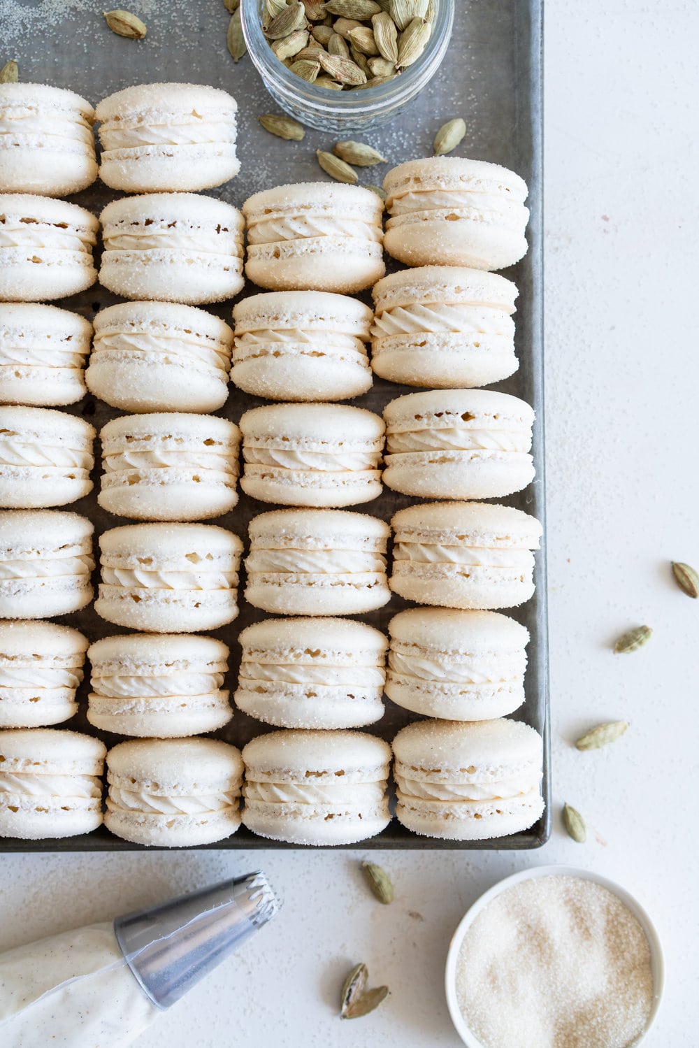 Golden Sugar Macarons with Cardamom Cream Cheese Filling. These French macarons are made with golden sugar, sprinkled with the sugar to give them a sparkly top, and filled with a smooth cardamom cream cheese filling. These are an easy gluten free treat, and this is a great go-to macaron recipe, filled with tips and tricks to help you master french macarons! #frenchmacarons #goldensugar #cardamomcreamcheese