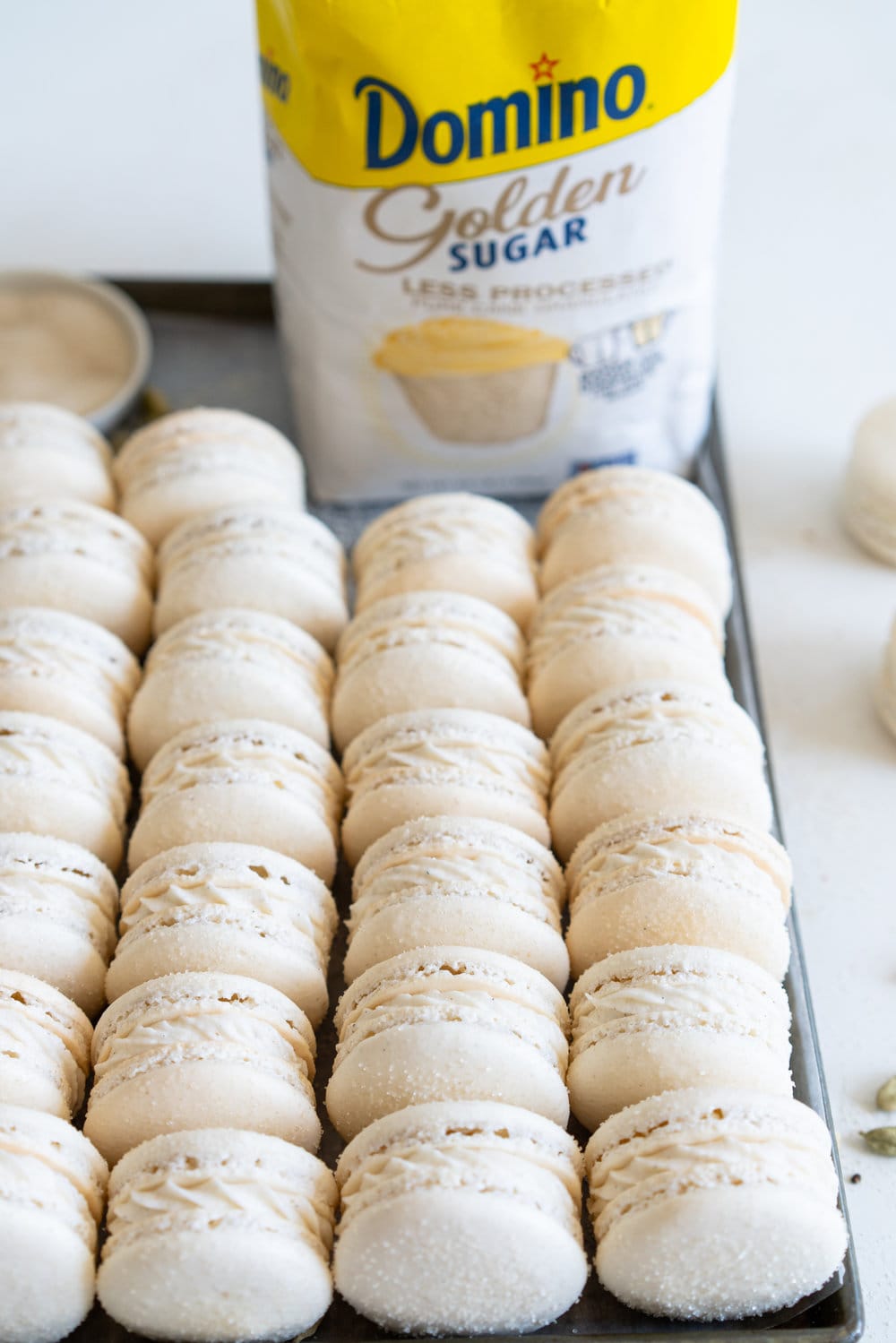 Golden Sugar Macarons with Cardamom Cream Cheese Filling. These French macarons are made with golden sugar, sprinkled with the sugar to give them a sparkly top, and filled with a smooth cardamom cream cheese filling. These are an easy gluten free treat, and this is a great go-to macaron recipe, filled with tips and tricks to help you master french macarons! #frenchmacarons #goldensugar #cardamomcreamcheese