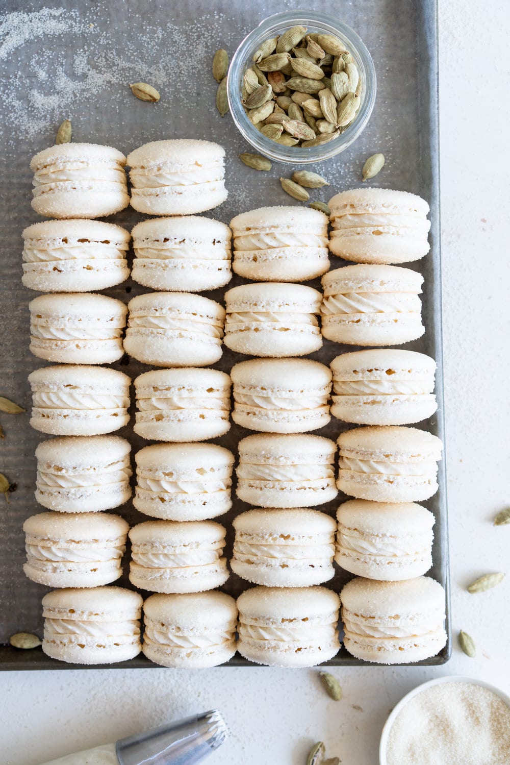 Golden Sugar Macarons with Cardamom Cream Cheese Filling. These French macarons are made with golden sugar, sprinkled with the sugar to give them a sparkly top, and filled with a smooth cardamom cream cheese filling. These are an easy gluten free treat, and this is a great go-to macaron recipe, filled with tips and tricks to help you master french macarons! #frenchmacarons #goldensugar #cardamomcreamcheese