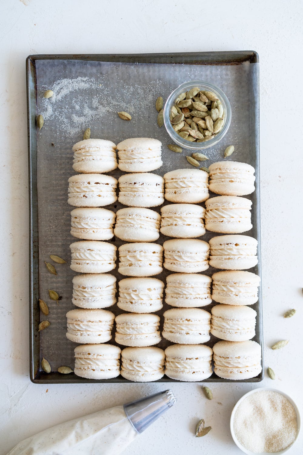 Golden Sugar Macarons with Cardamom Cream Cheese Filling. These French macarons are made with golden sugar, sprinkled with the sugar to give them a sparkly top, and filled with a smooth cardamom cream cheese filling. These are an easy gluten free treat, and this is a great go-to macaron recipe, filled with tips and tricks to help you master french macarons! #frenchmacarons #goldensugar #cardamomcreamcheese