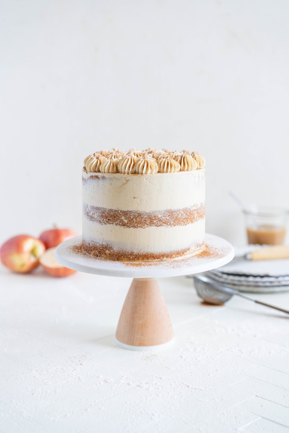 Spiced Brown Sugar cake with Cinnamon Apple Filling and Maple Caramel German Buttercream. This layer cake screams fall - a cozy brown sugar spice cake is layered with a cinnamon apple filling and a maple caramel german buttercream, then finished with a maple salted caramel drizzle and a dusting of cinnamon. This is the perfect fall inspired layer cake #autumncake #applecake #layercake