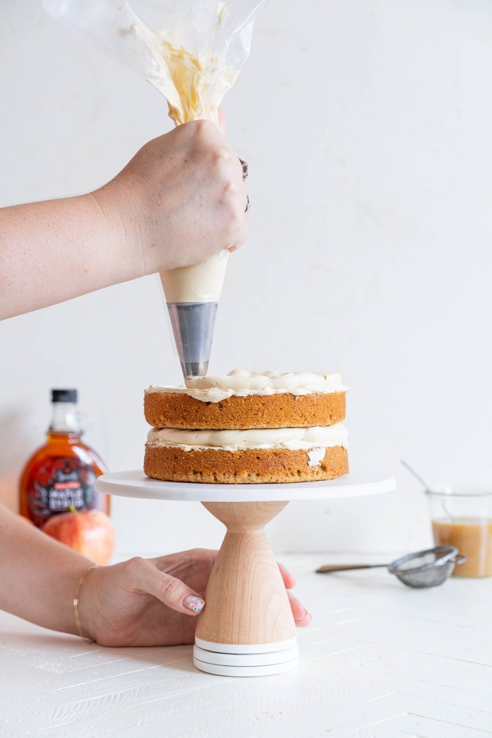 Spiced Brown Sugar cake with Cinnamon Apple Filling and Maple Caramel German Buttercream. This layer cake screams fall - a cozy brown sugar spice cake is layered with a cinnamon apple filling and a maple caramel german buttercream, then finished with a maple salted caramel drizzle and a dusting of cinnamon. This is the perfect fall inspired layer cake #autumncake #applecake #layercake