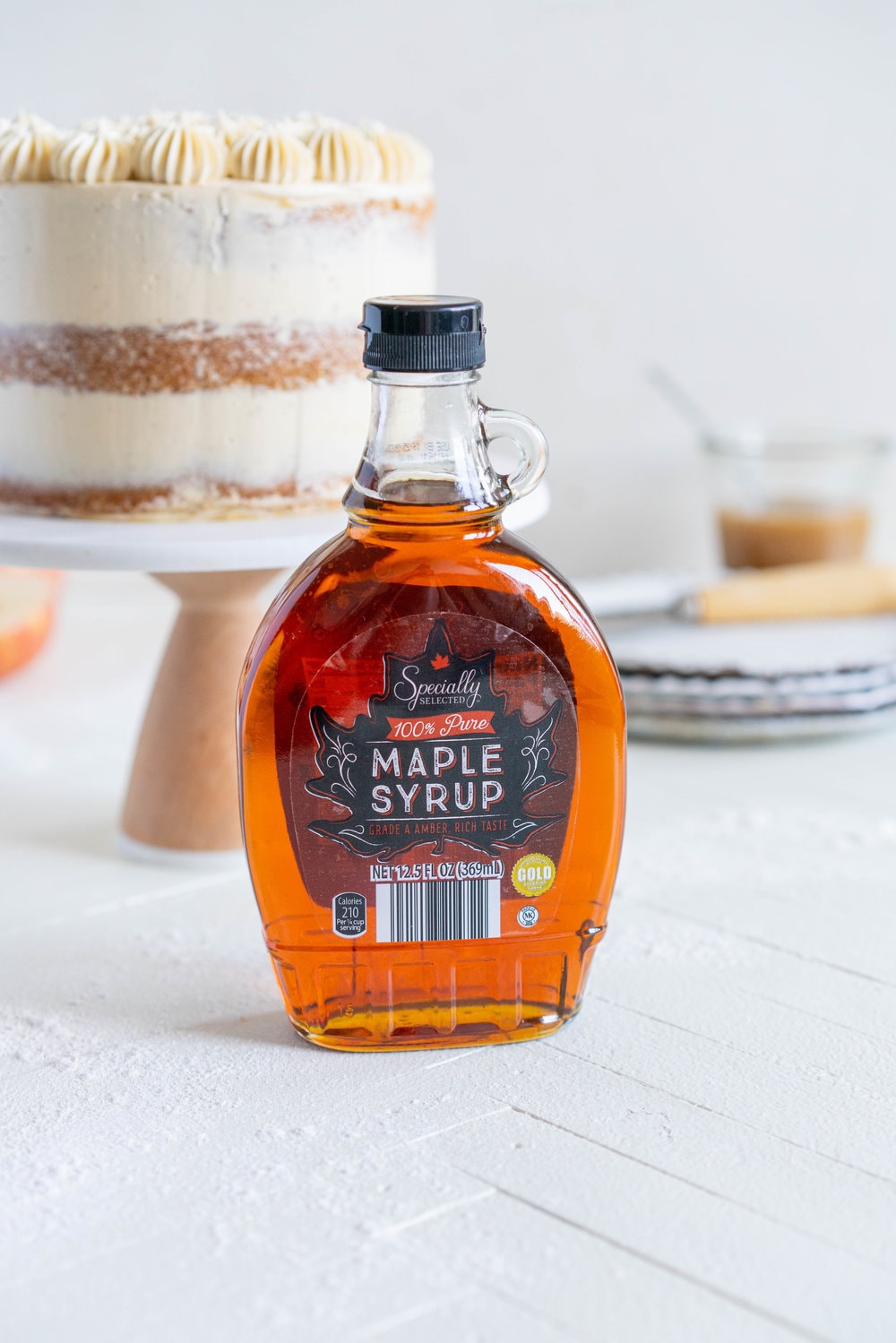 Spiced Brown Sugar cake with Cinnamon Apple Filling and Maple Caramel German Buttercream. This layer cake screams fall - a cozy brown sugar spice cake is layered with a cinnamon apple filling and a maple caramel german buttercream, then finished with a maple salted caramel drizzle and a dusting of cinnamon. This is the perfect fall inspired layer cake #autumncake #applecake #layercake