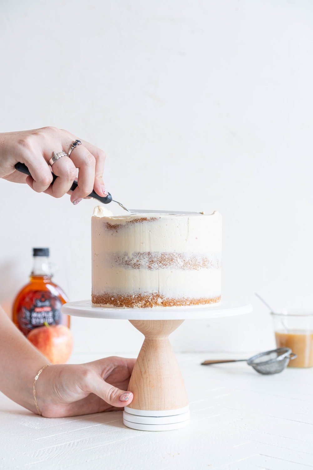 Spiced Brown Sugar cake with Cinnamon Apple Filling and Maple Caramel German Buttercream. This layer cake screams fall - a cozy brown sugar spice cake is layered with a cinnamon apple filling and a maple caramel german buttercream, then finished with a maple salted caramel drizzle and a dusting of cinnamon. This is the perfect fall inspired layer cake #autumncake #applecake #layercake