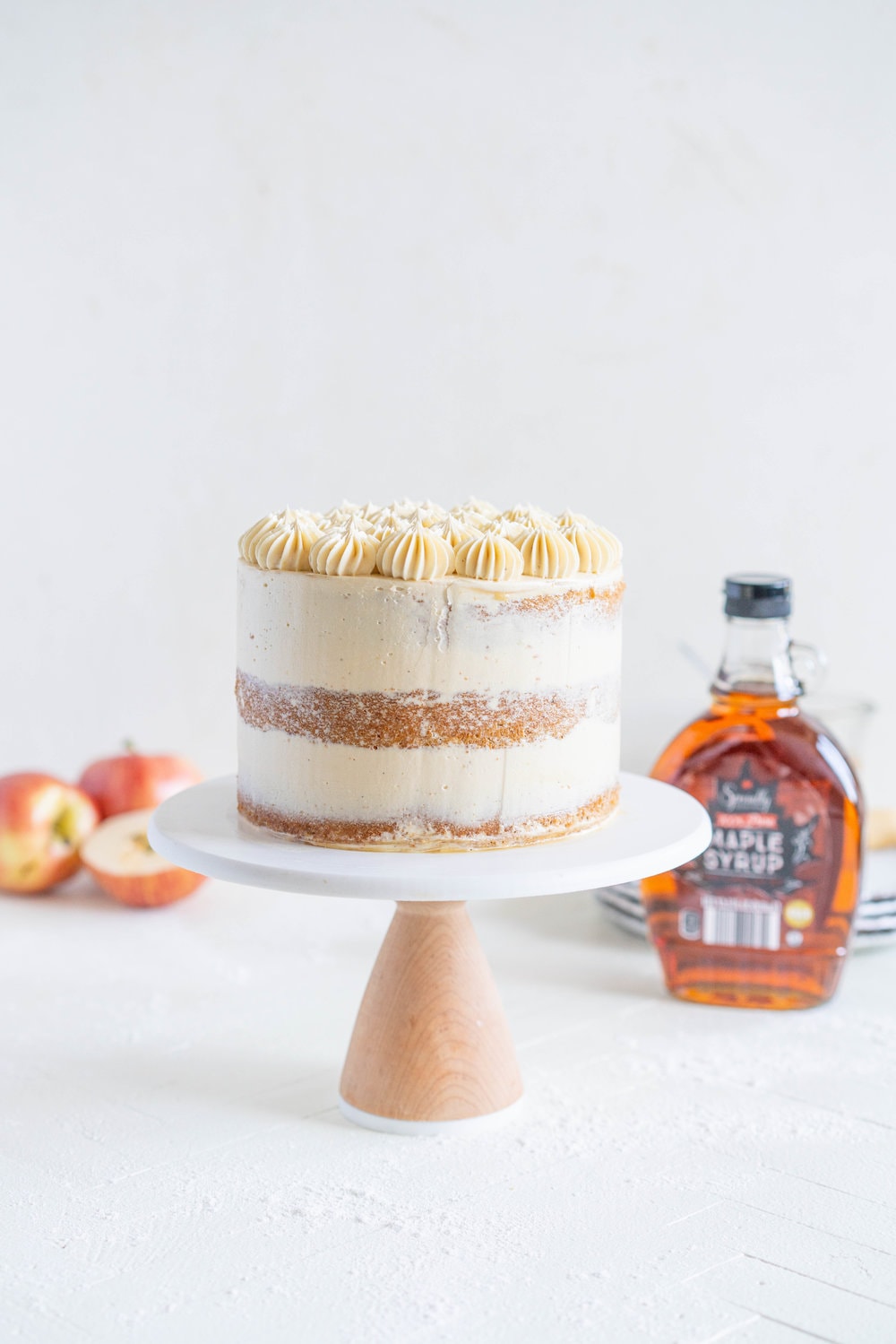 Spiced Brown Sugar cake with Cinnamon Apple Filling and Maple Caramel German Buttercream. This layer cake screams fall - a cozy brown sugar spice cake is layered with a cinnamon apple filling and a maple caramel german buttercream, then finished with a maple salted caramel drizzle and a dusting of cinnamon. This is the perfect fall inspired layer cake #autumncake #applecake #layercake