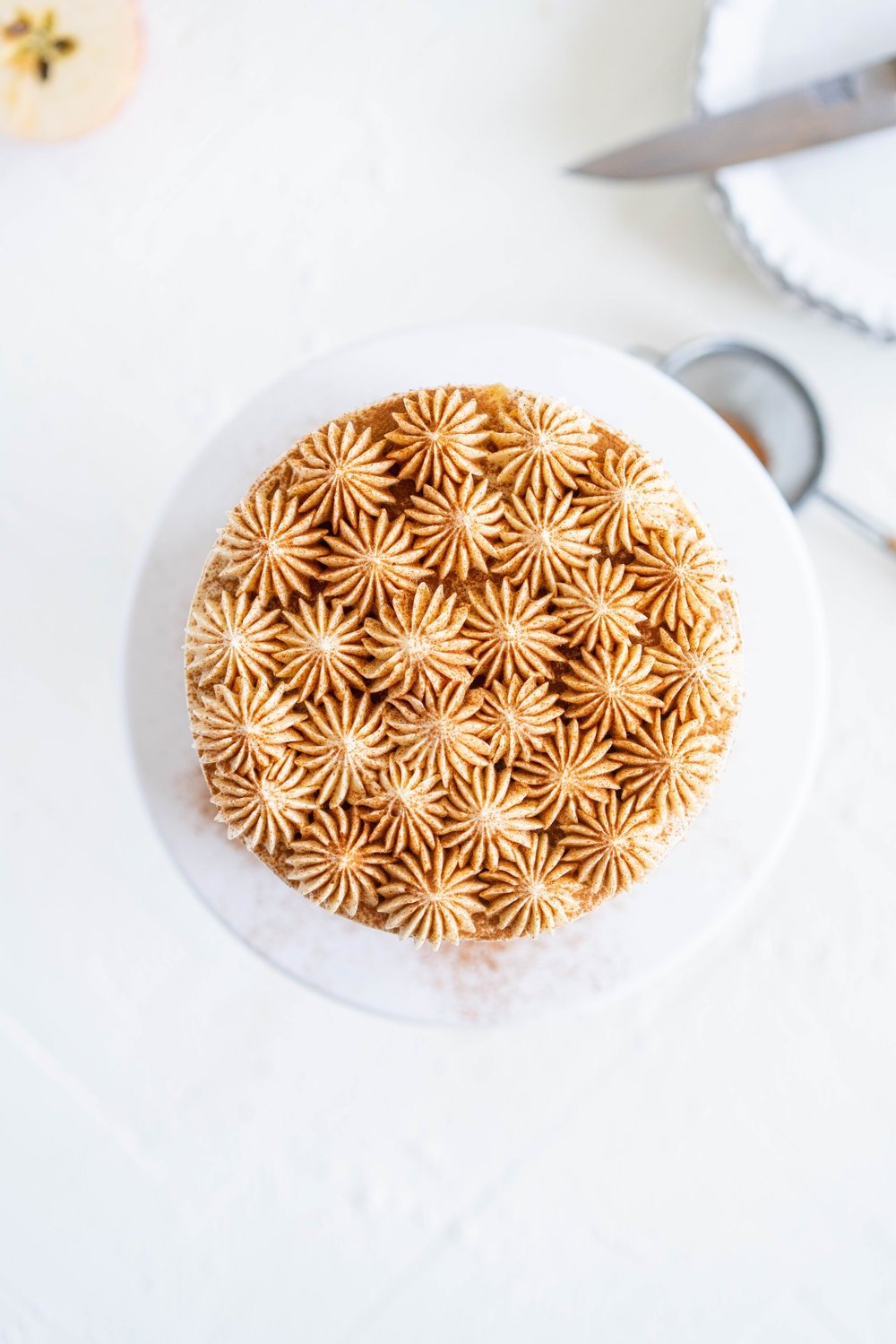 Spiced Brown Sugar cake with Cinnamon Apple Filling and Maple Caramel German Buttercream. This layer cake screams fall - a cozy brown sugar spice cake is layered with a cinnamon apple filling and a maple caramel german buttercream, then finished with a maple salted caramel drizzle and a dusting of cinnamon. This is the perfect fall inspired layer cake #autumncake #applecake #layercake